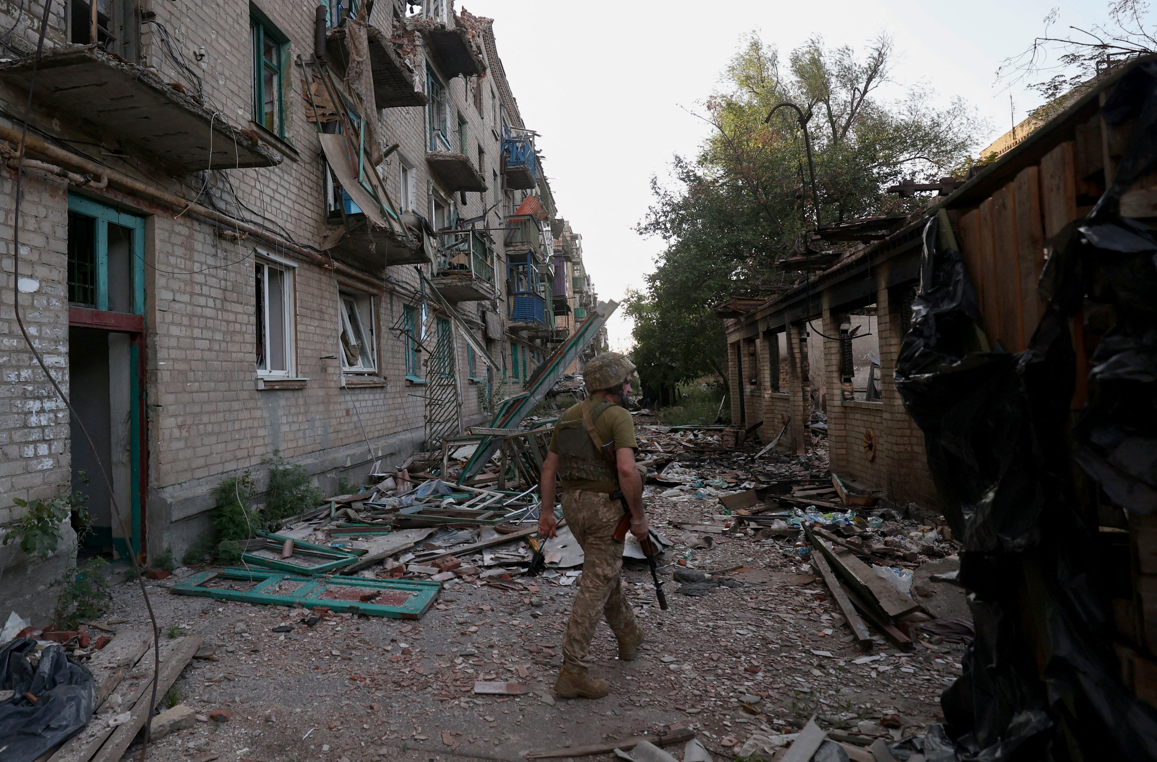 File: A Ukrainian serviceman of the 225th Separate Assault Battalion patrols as he walks past buildings heavily damaged by artillery fire in the town of Chasiv Yar, Donetsk region, on 24 July 2024