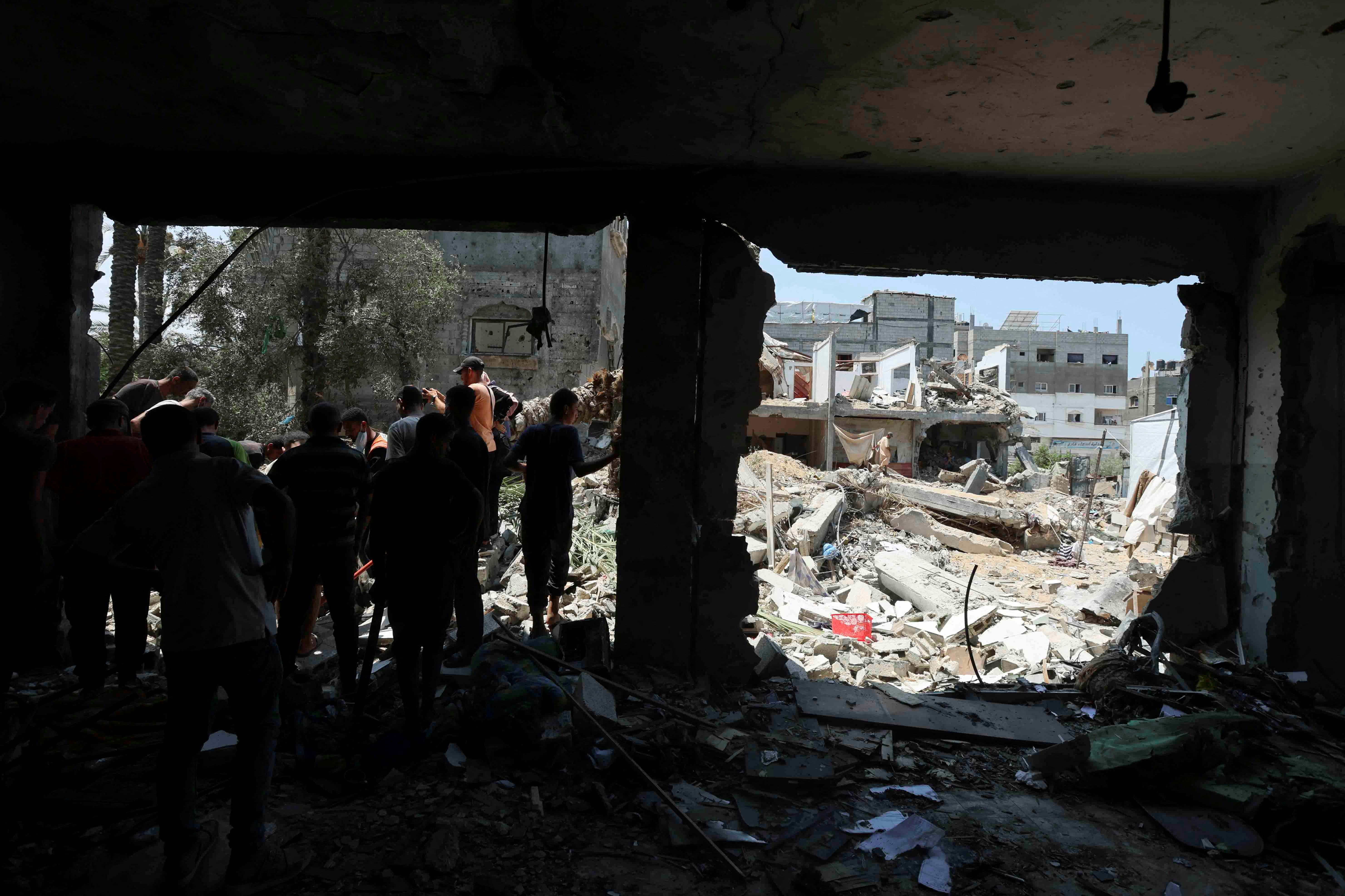 Palestinians inspect a school sheltering displaced people following an Israeli strike