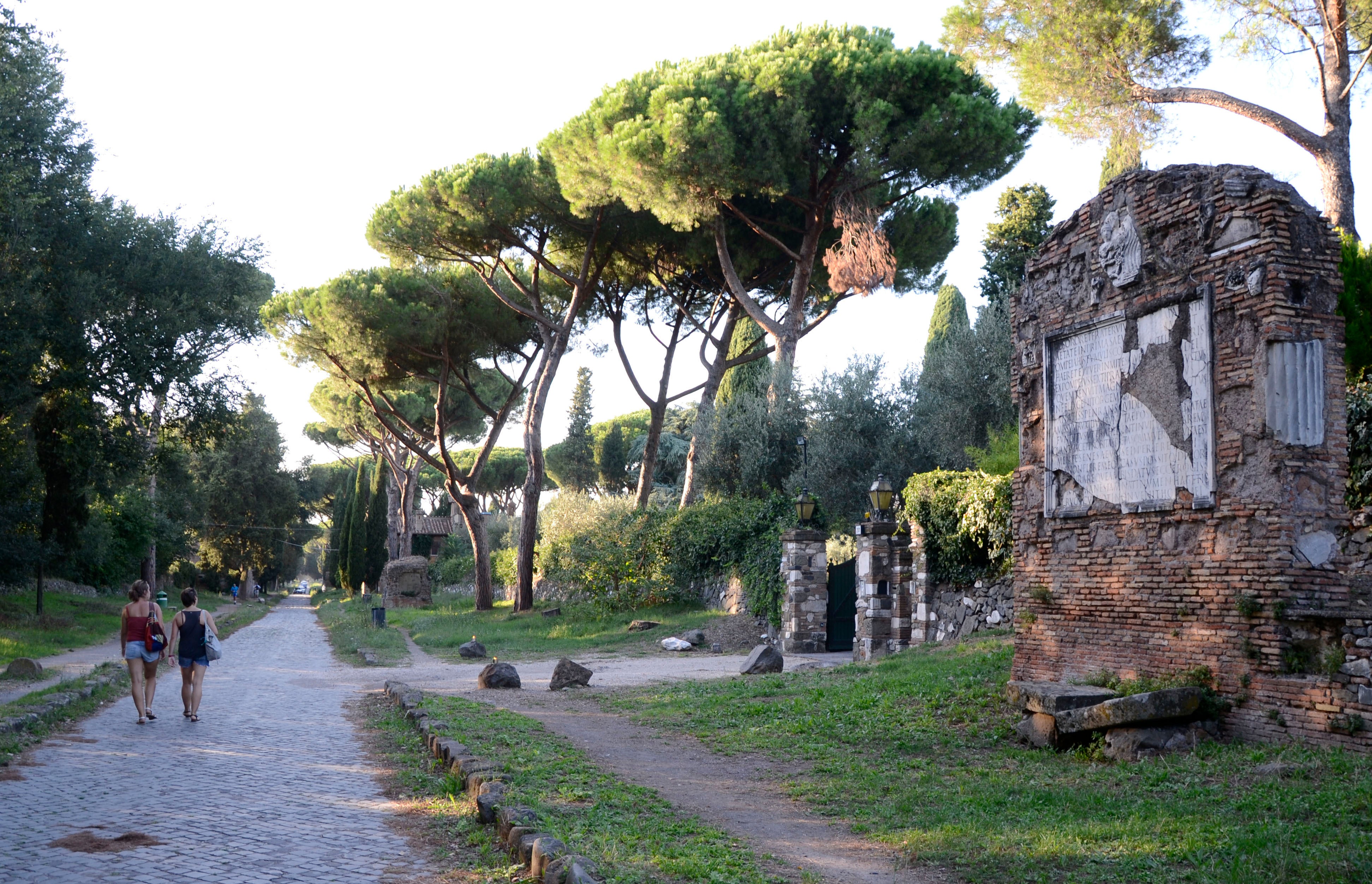 People walk past ruins along the Appia Antica, the ancient Roman Appian Way, in Rome