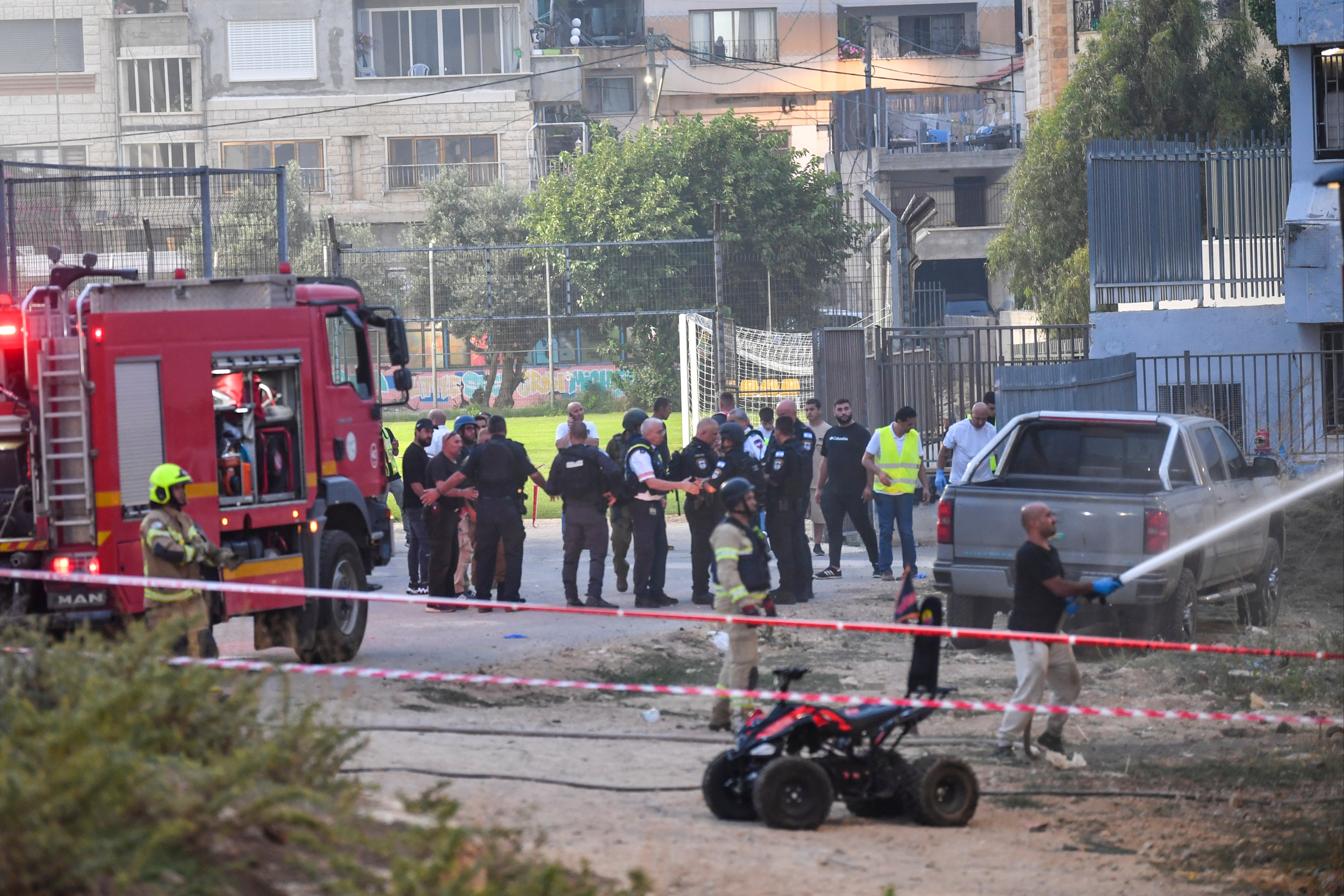 Israeli police officers and firefighters work at the site of a rocket attack in Majdal Shams, in the Israeli-controlled Golan Heights