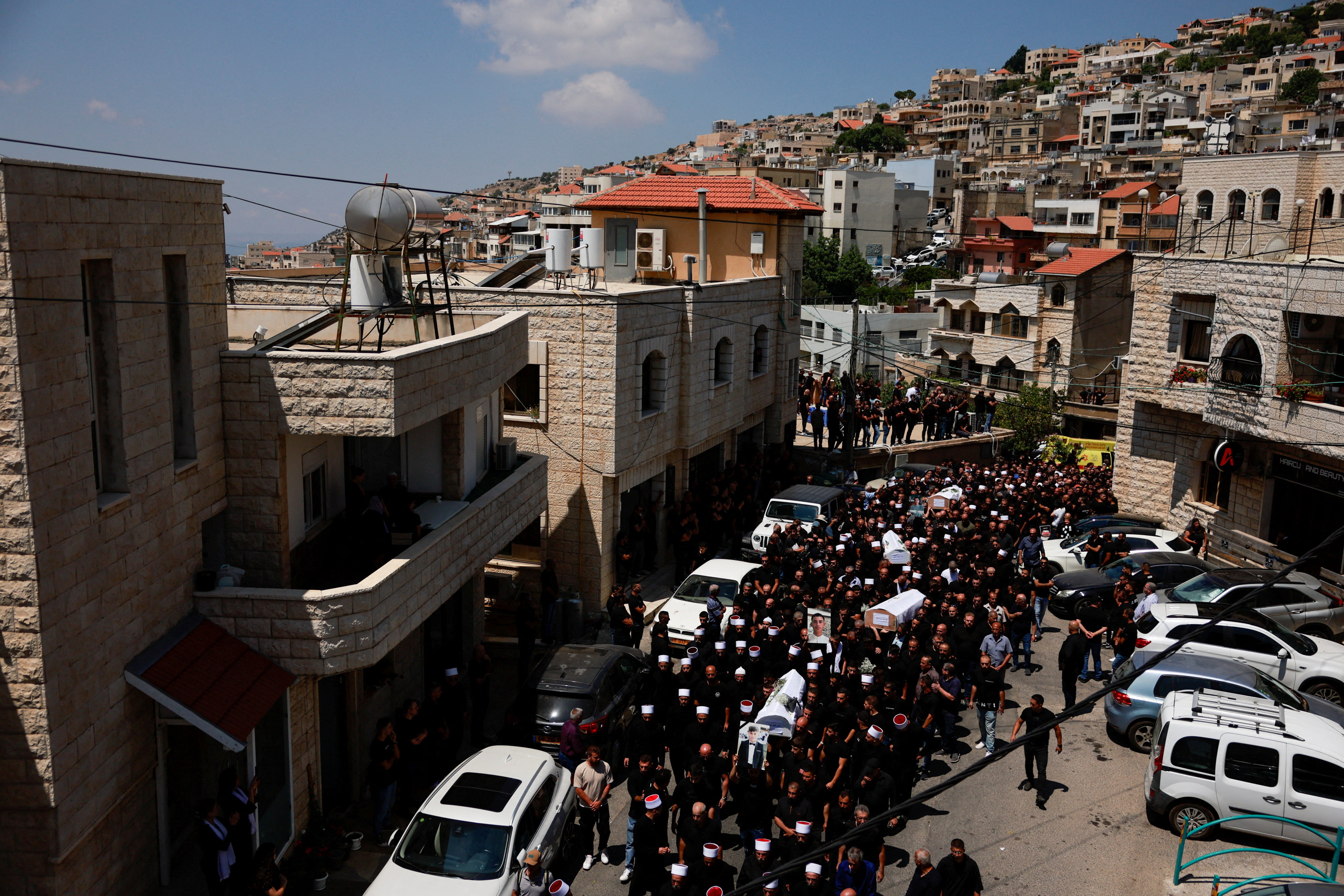 Mourners carry coffins during the funeral of those killed in the attack on a football pitch