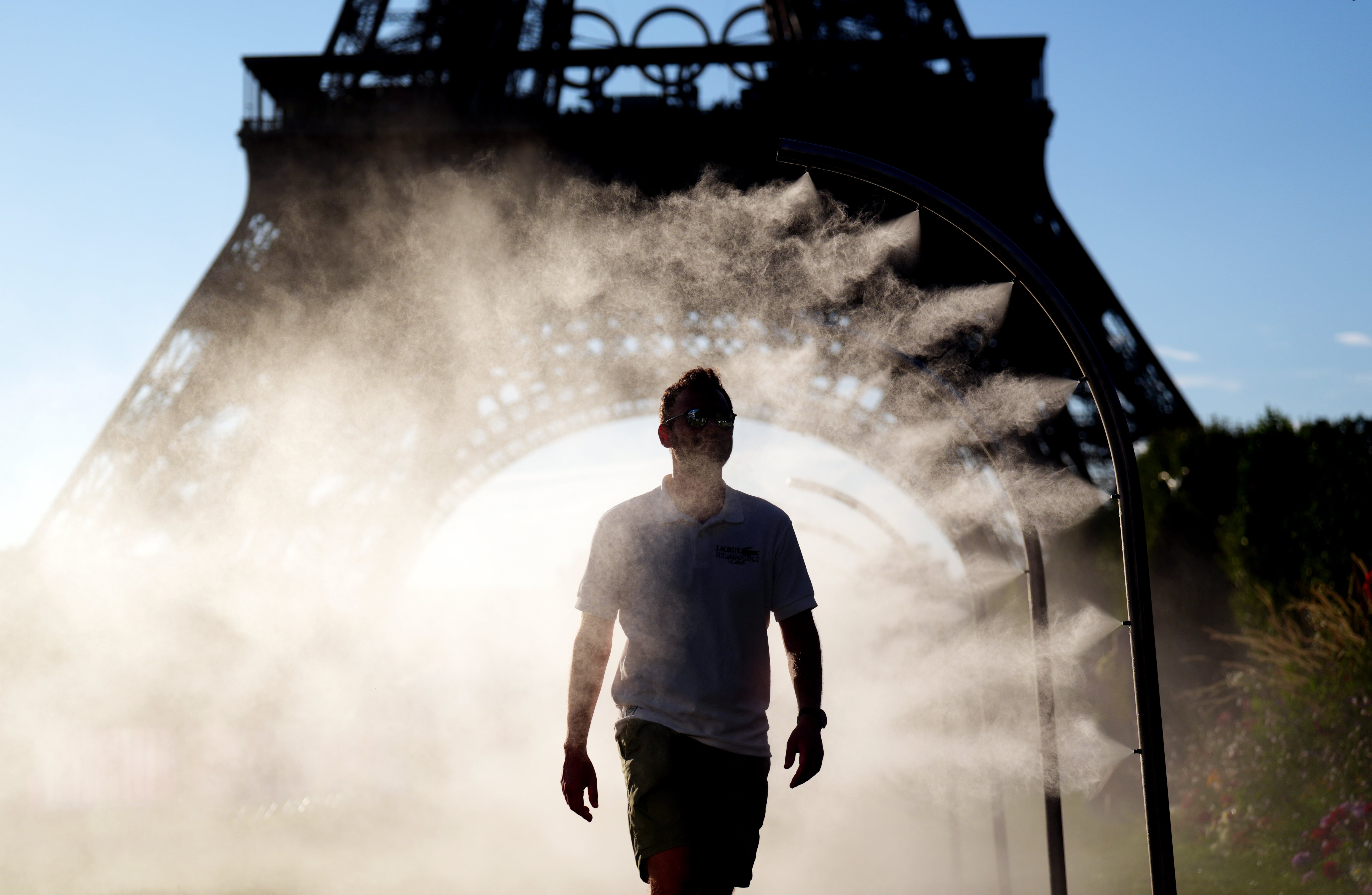 Fans walk through a mist of water near the Eiffel Tower (John Walton/PA)