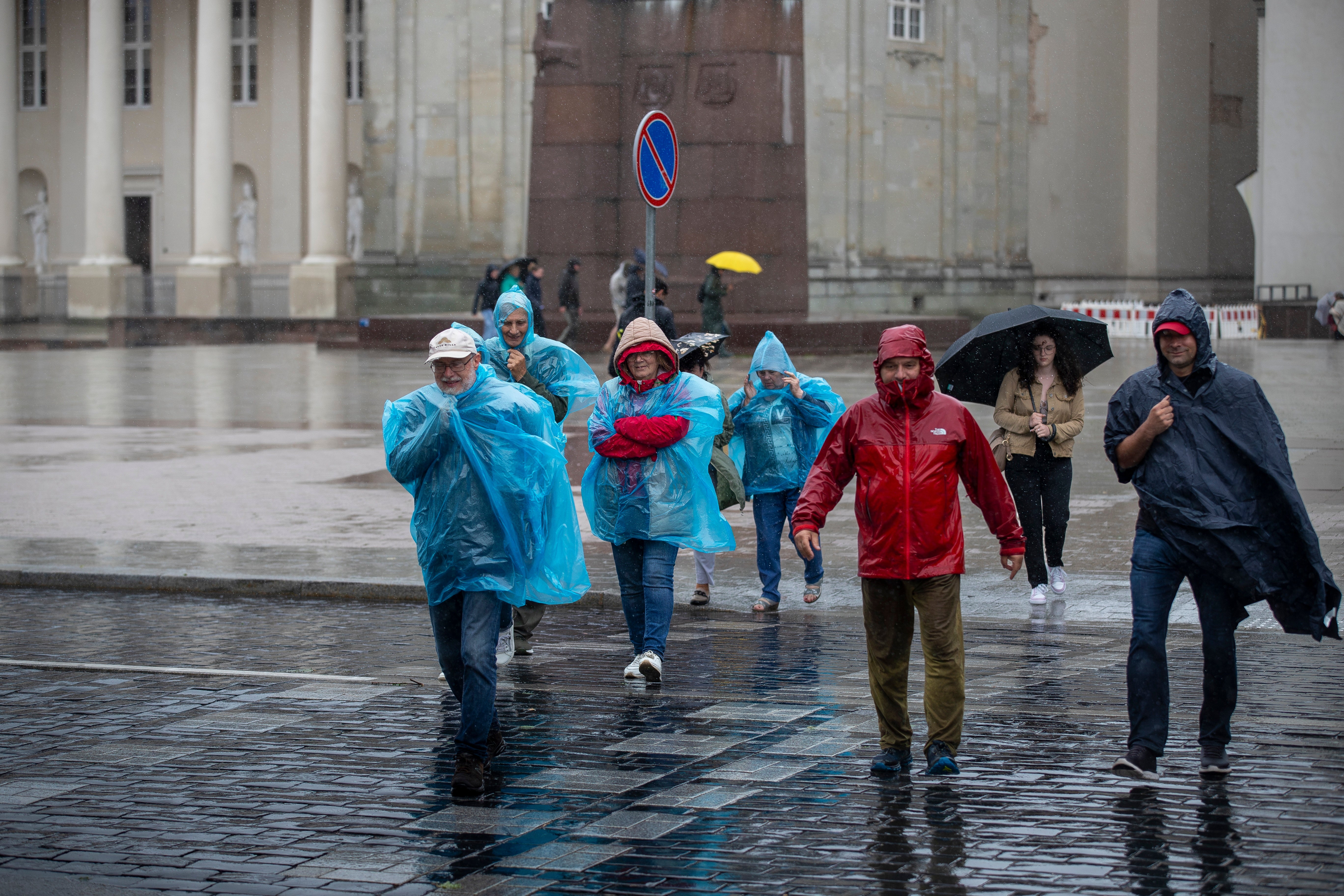 People cross a street during a rainy day, in Vilnius, Lithuania, Monday, July 29, 2024