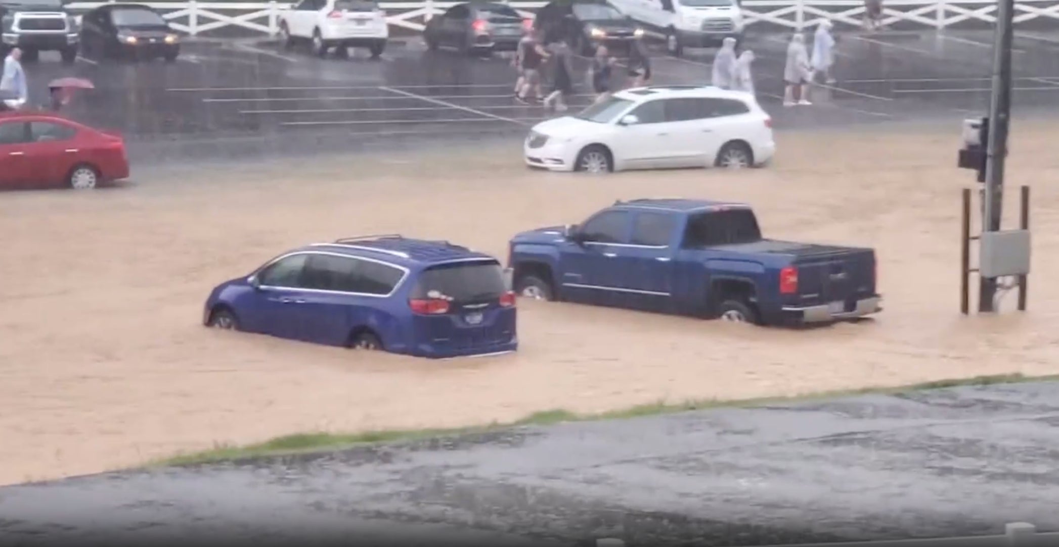 People rush through a parking lot at Dollywood as floodwaters stream through the theme park