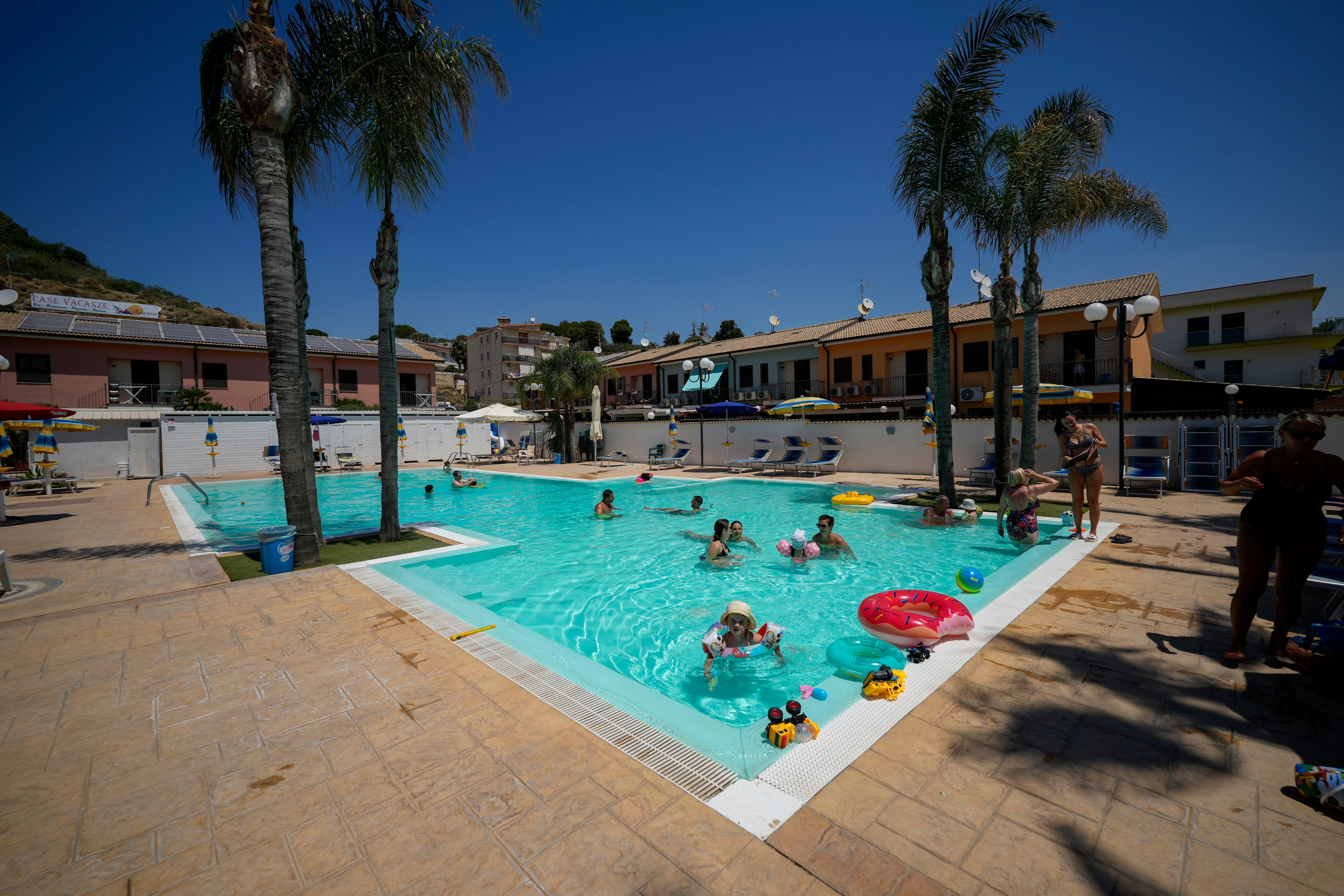 Tourists enjoy the swimming pool of the ‘L’Ancora’ holiday resort in the sea town of Porto Empedocle, in southern Sicily