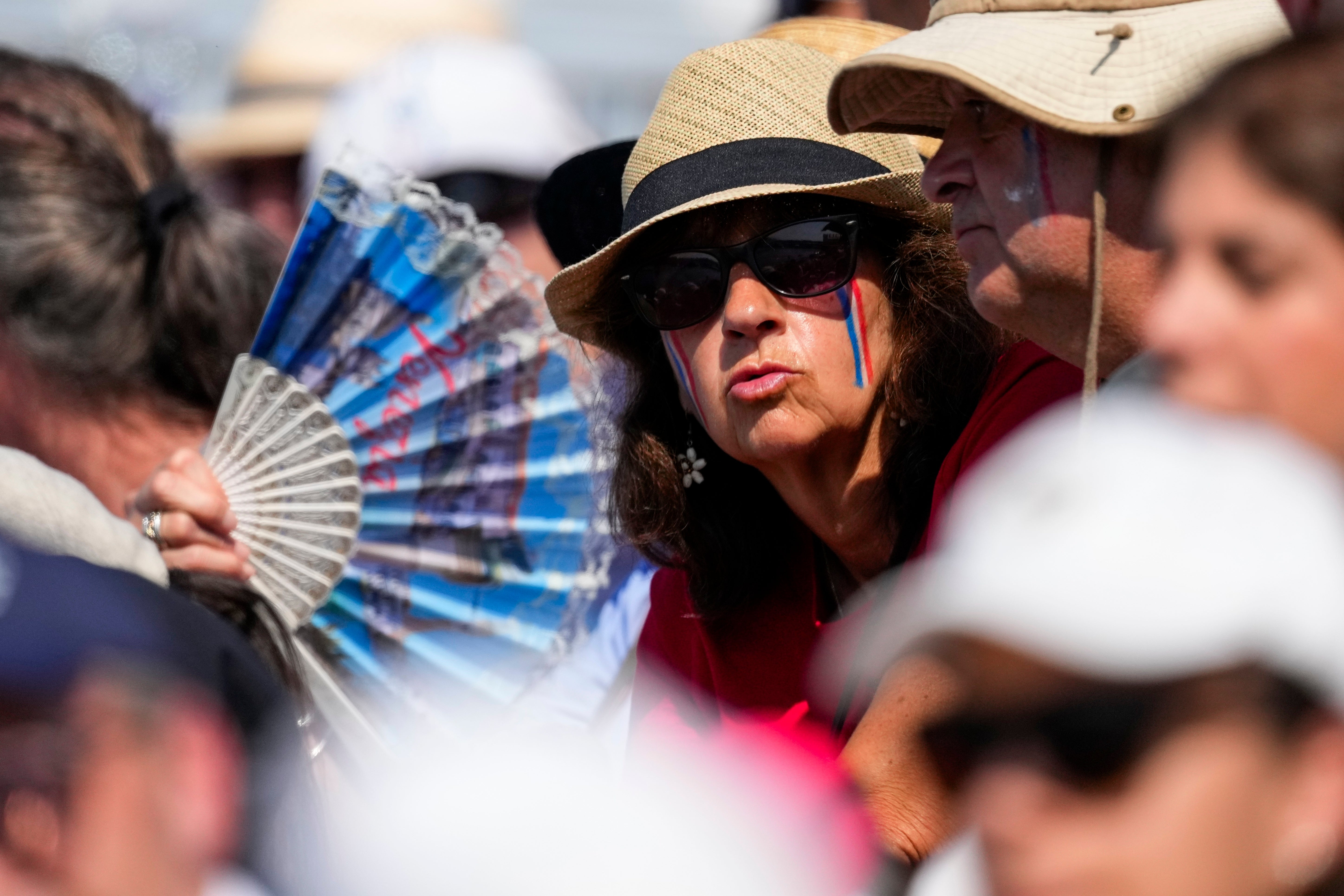 A fan tries to cool off during rowing competitions at the 2024 Summer Olympics, Monday, July 29, 2024