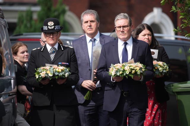 <p>Keir Starmer carries a floral tribute to the child victims of Monday’s knife attack in Southport</p>