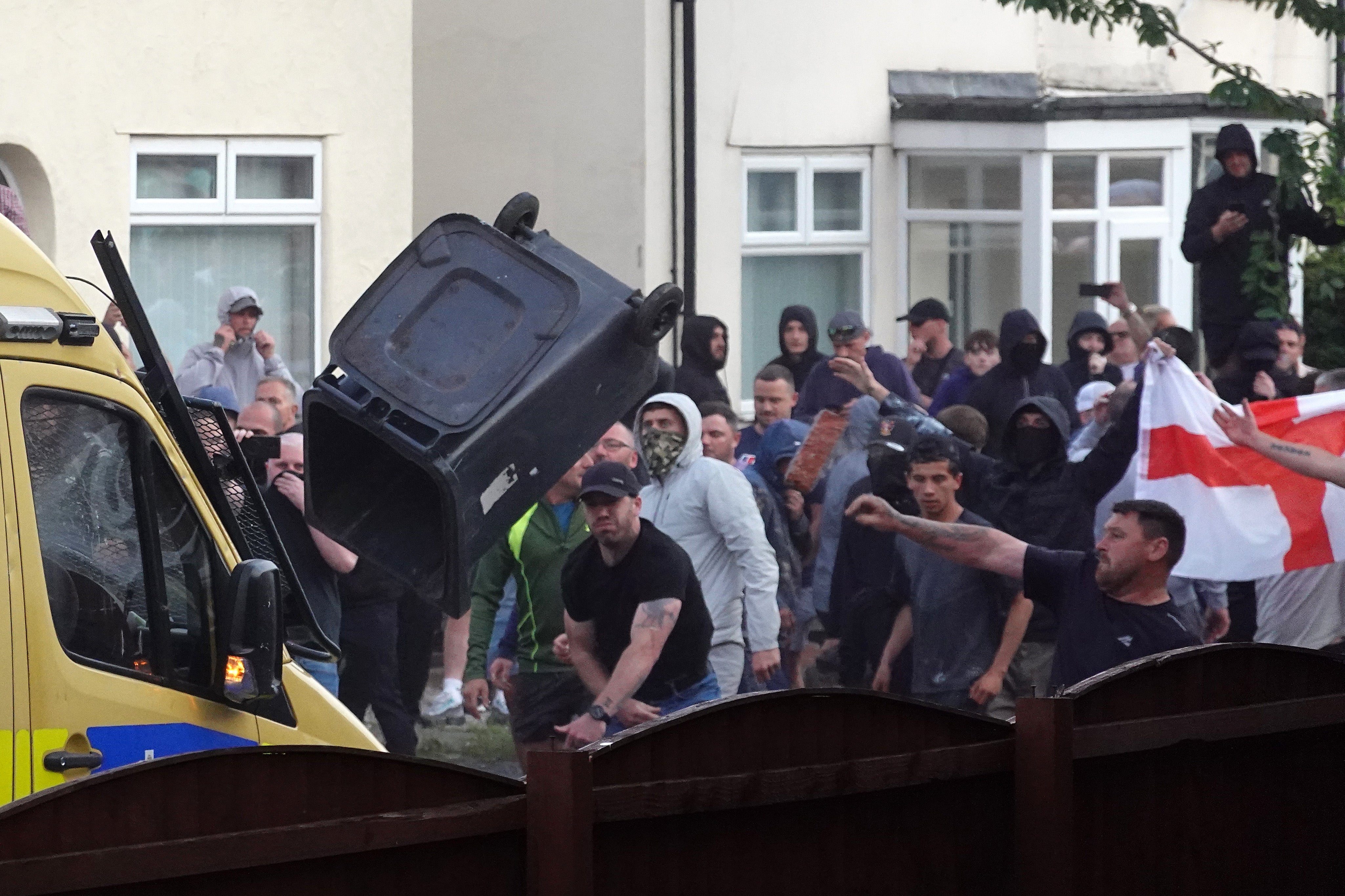 Far-right protesters throw wheelie bins at a police in Southport on Tuesday