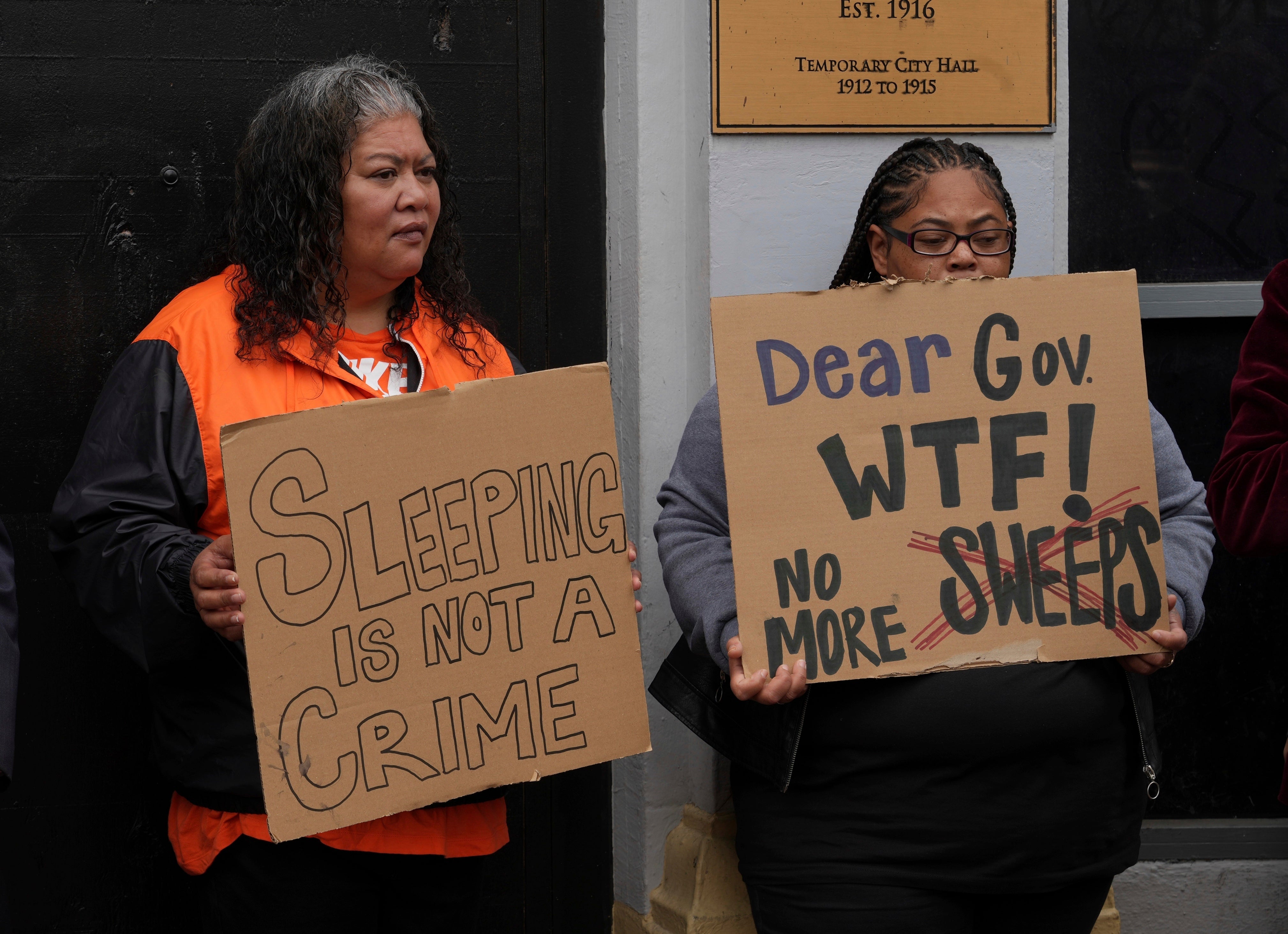 Activists hold signs at a news conference opposing Mayor London Breed's crackdown on homeless encampments in San Francisco