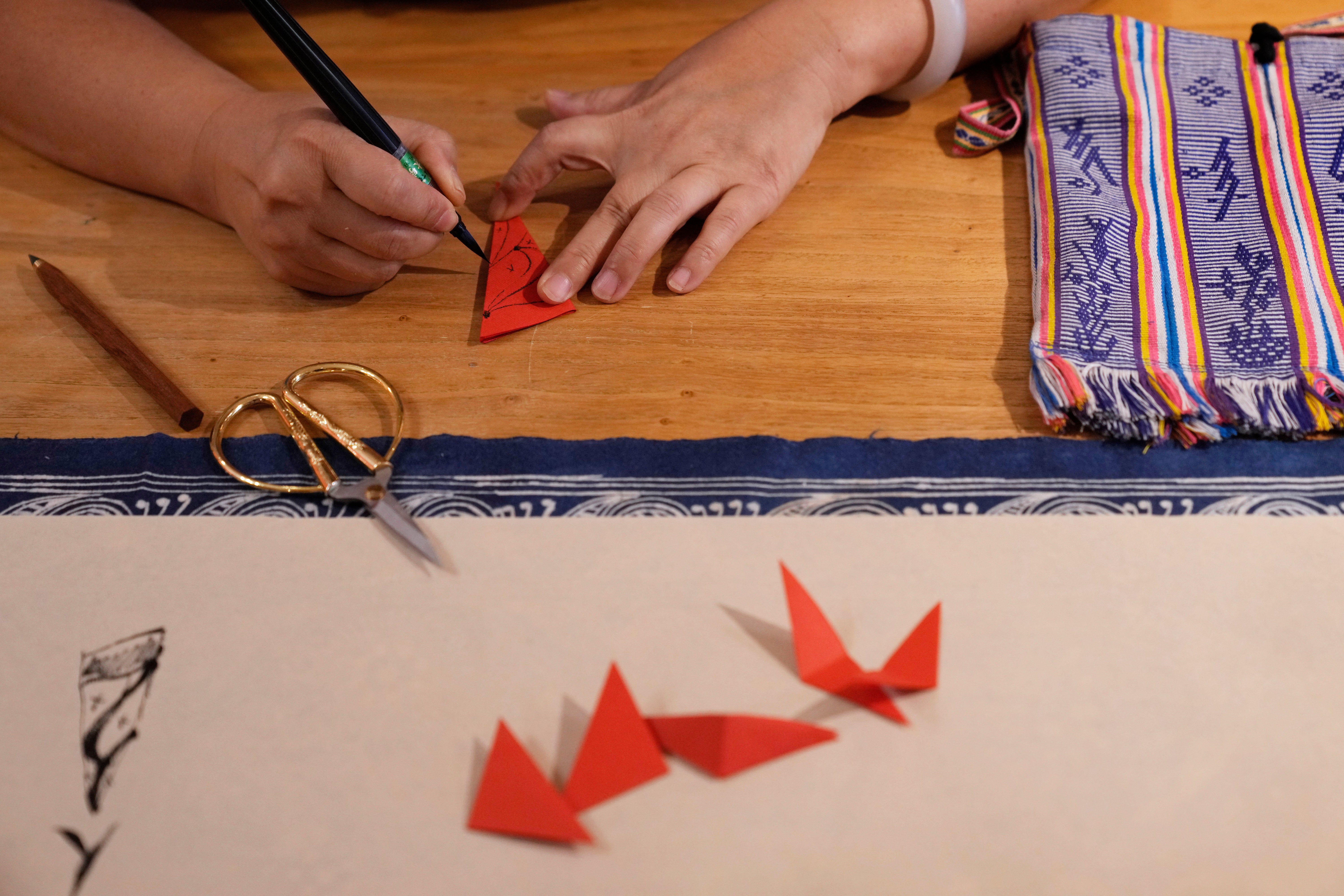 Xu Yan, an author of a textbook on nüshu, a centuries-old secret script, writes nüshu on paper cuttings at her studi