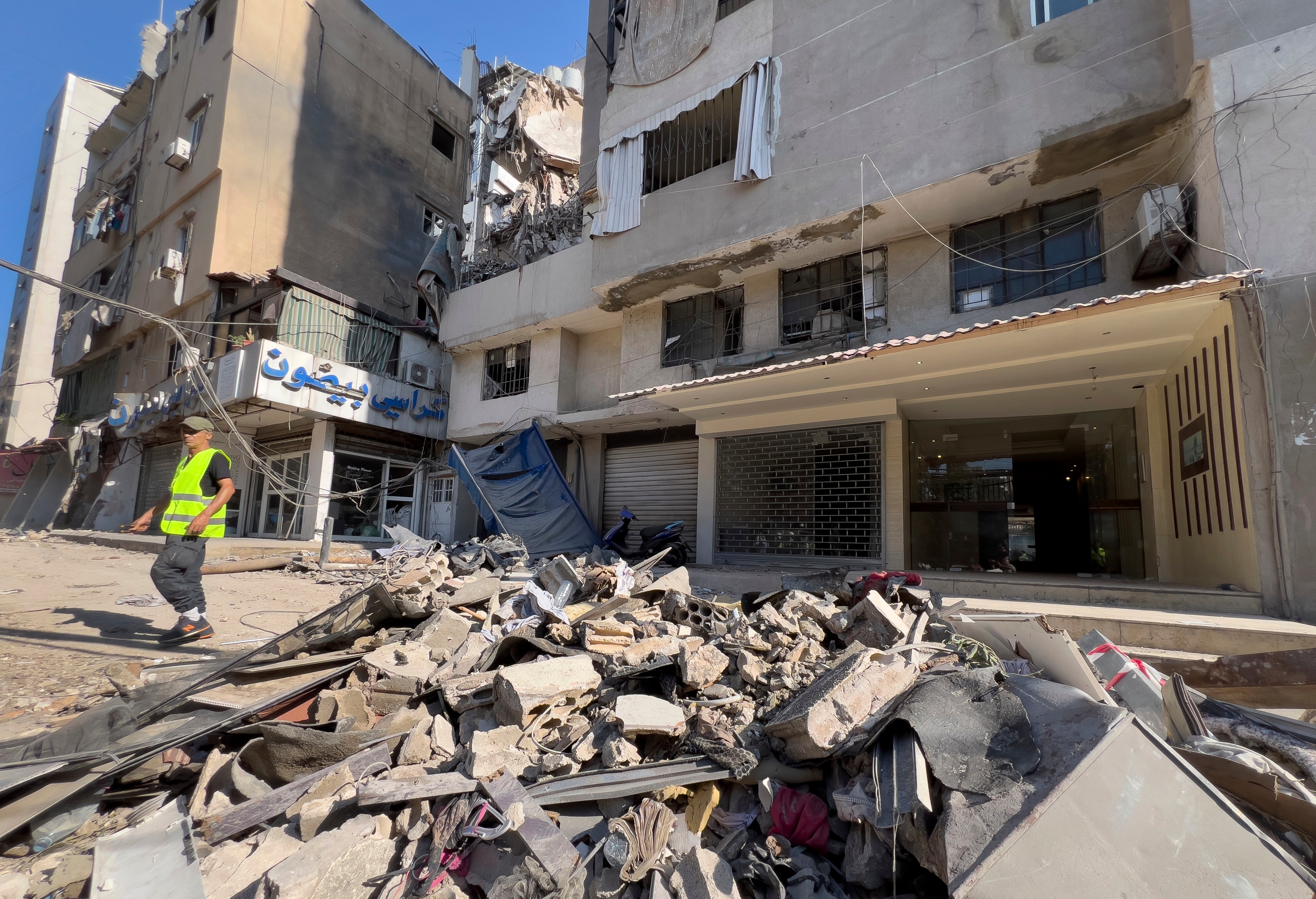 A municipality worker passes by debris of damaged buildings that were hit by an Israeli airstrike on Tuesday evening in the southern suburbs of Beirut, Lebanon