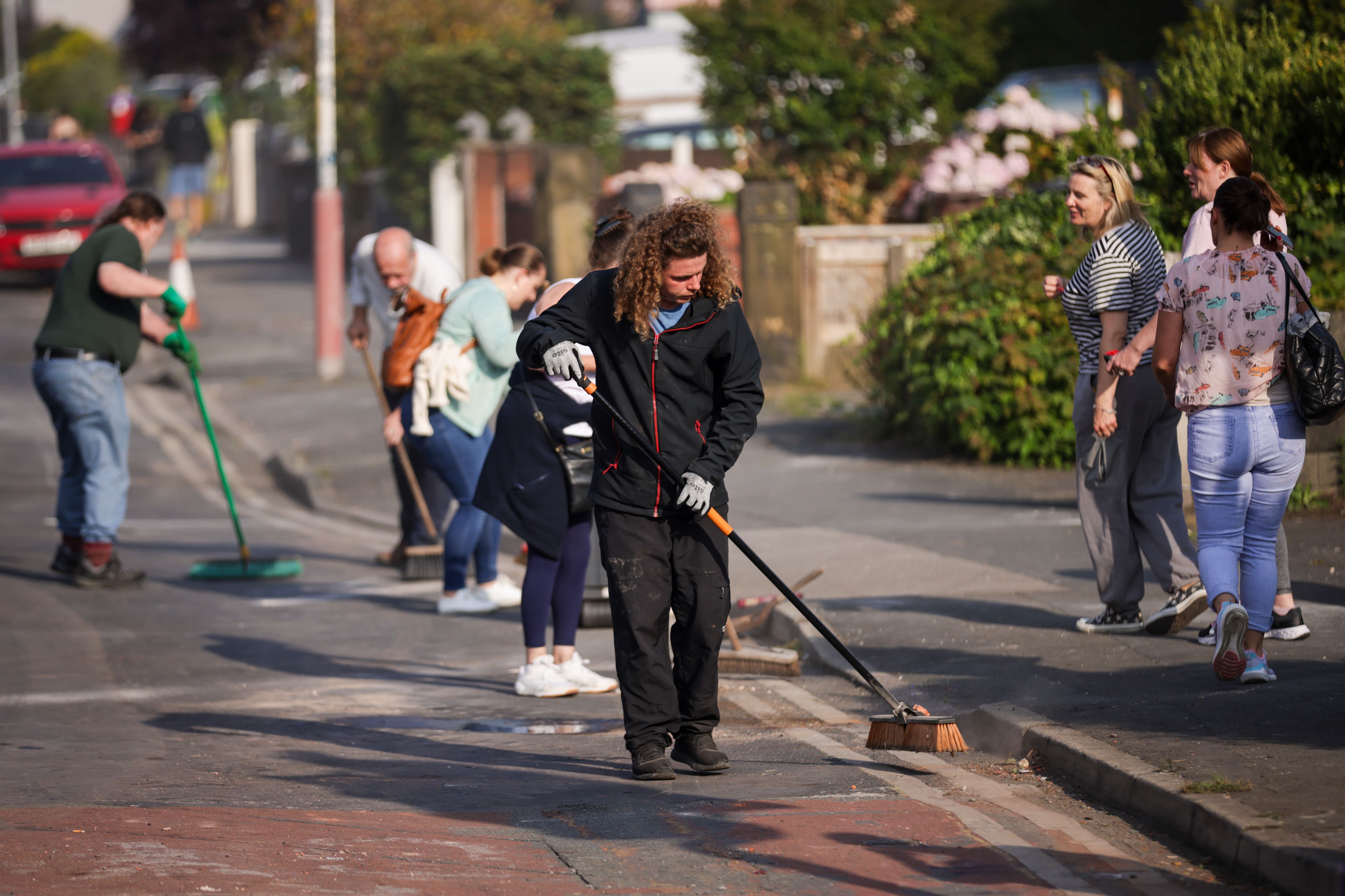 Volunteers sweep Sussex Road in Southport, Merseyside, after rioters attacked police