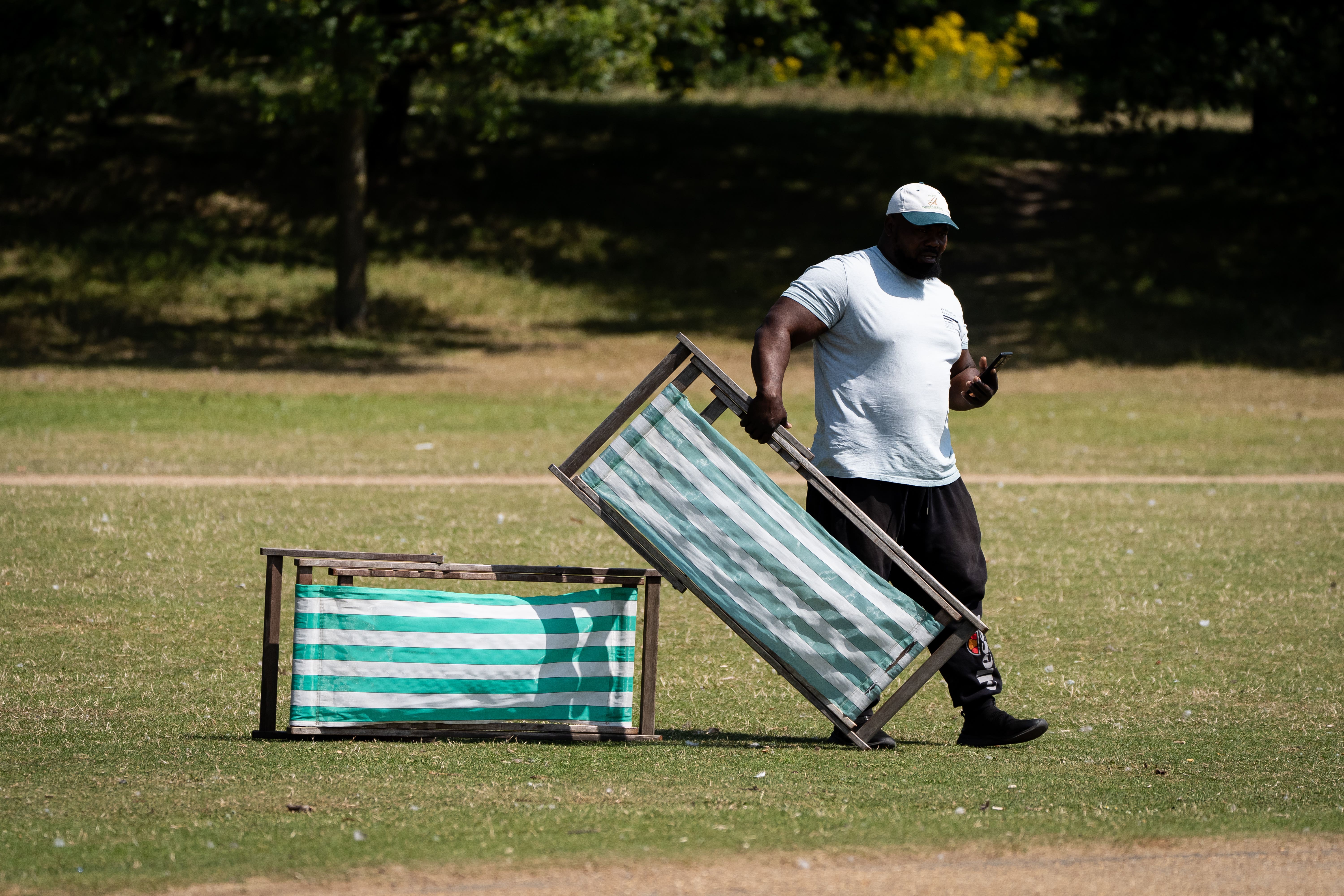 A person holds a deck chair in Hyde Park, London (Aaron Chown/PA)