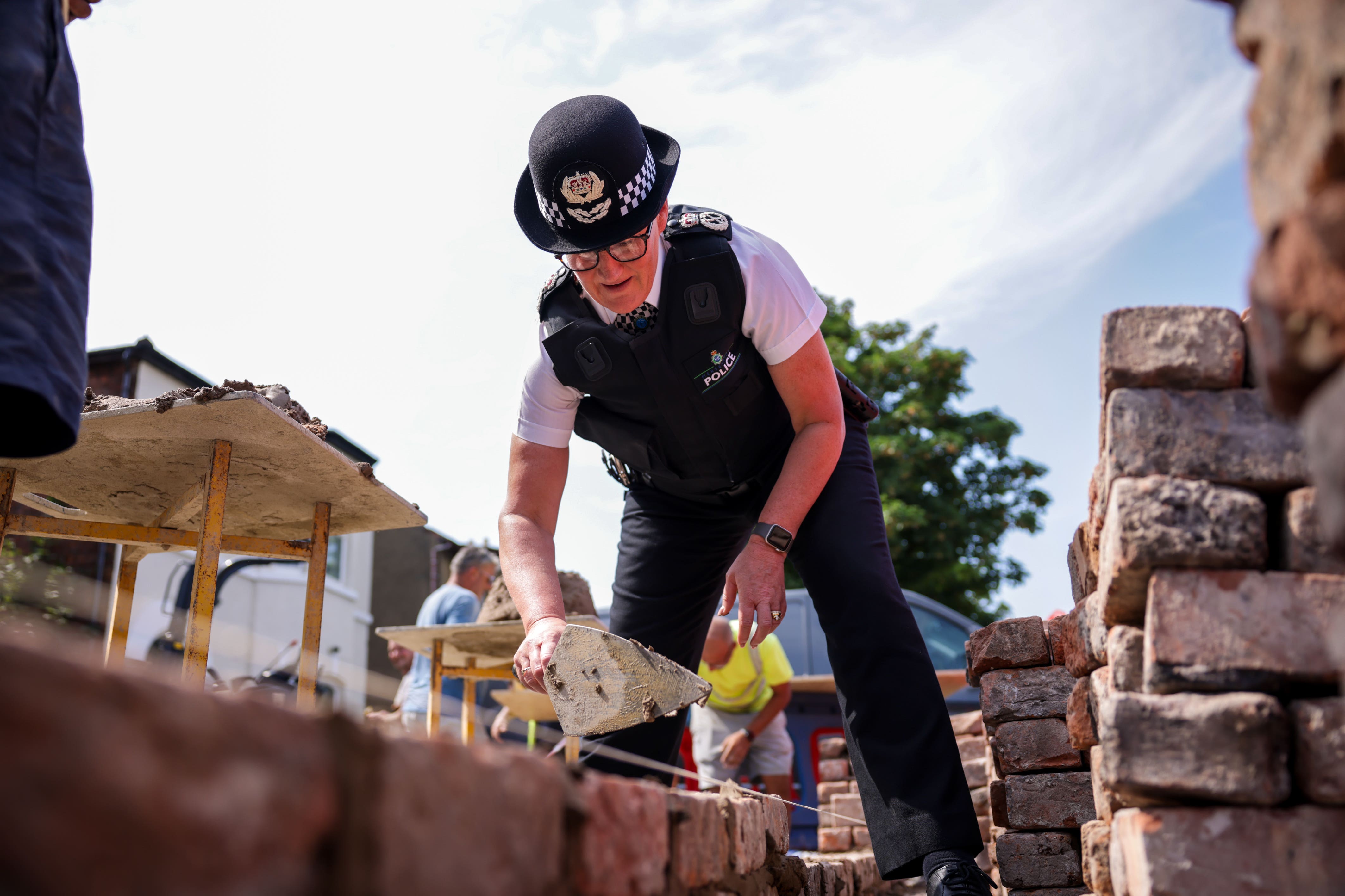 Chief Constable Serena Kennedy helps rebuild a wall outside the Southport Islamic Centre Mosque (James Speakman/PA)