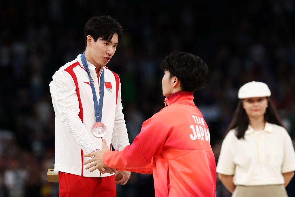 Silver medallist Zhang Boheng of China shakes hands with Gold medallist Shinnosuke Oka