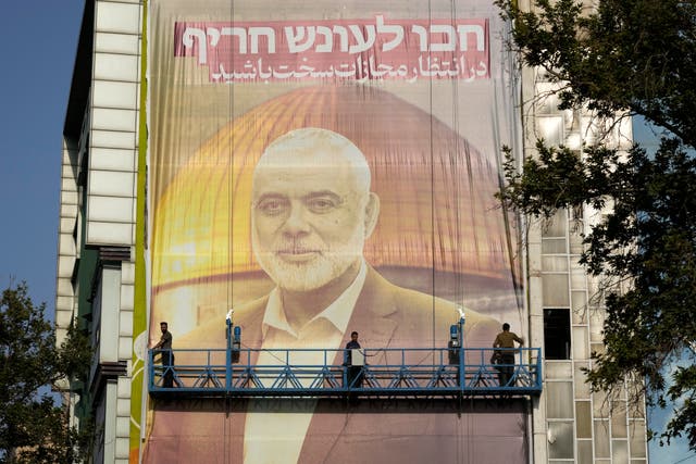 <p>Iranian workers install a huge banner on a wall showing a portrait of Hamas leader Ismail Haniyeh and the Dome of Rock Mosque at the Al-Aqsa Mosque compound of Jerusalem </p>