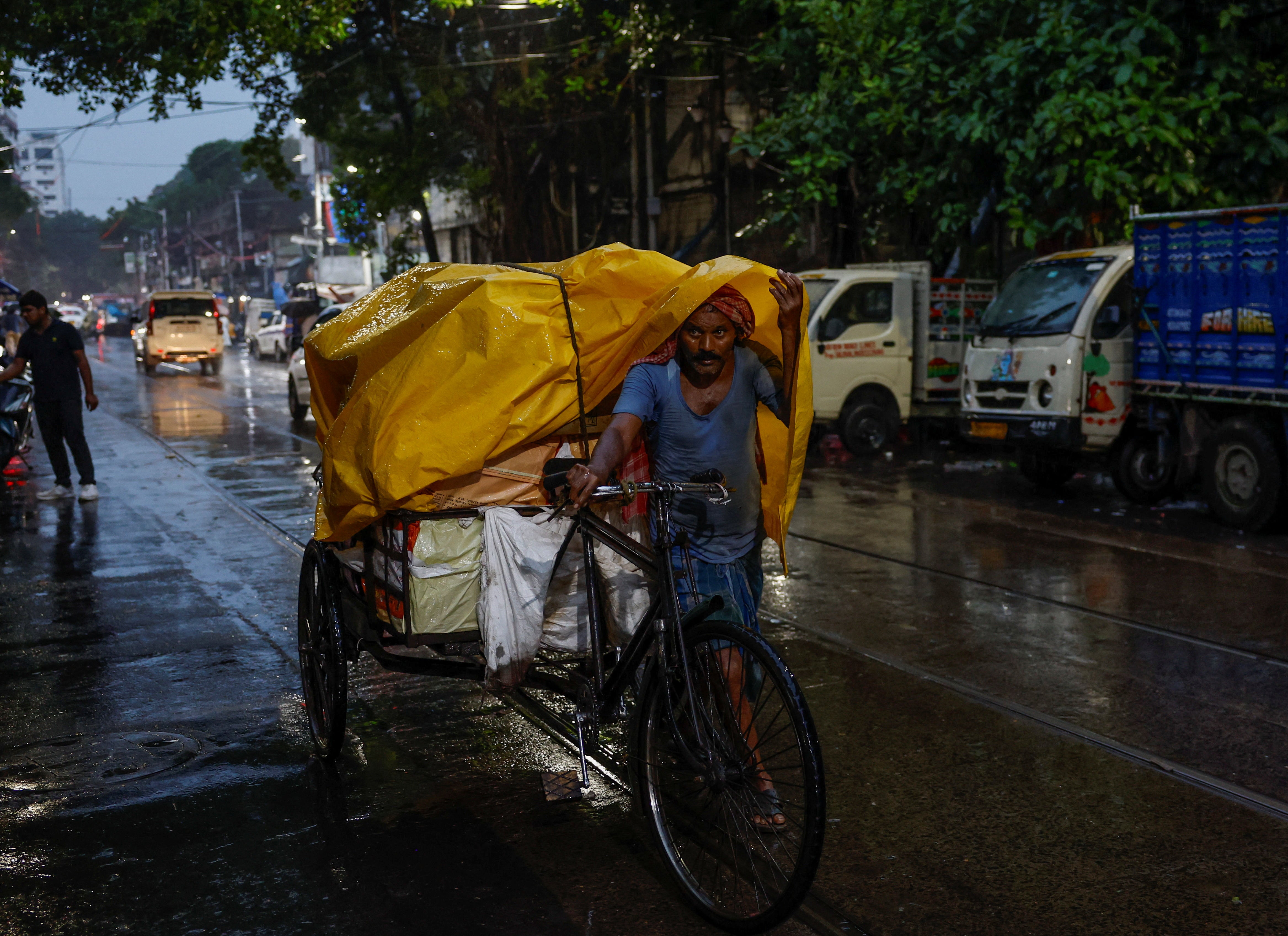 A man pulls a cart packed with goods as he wades through the rain on a street in Kolkata, India, 31 July 2024