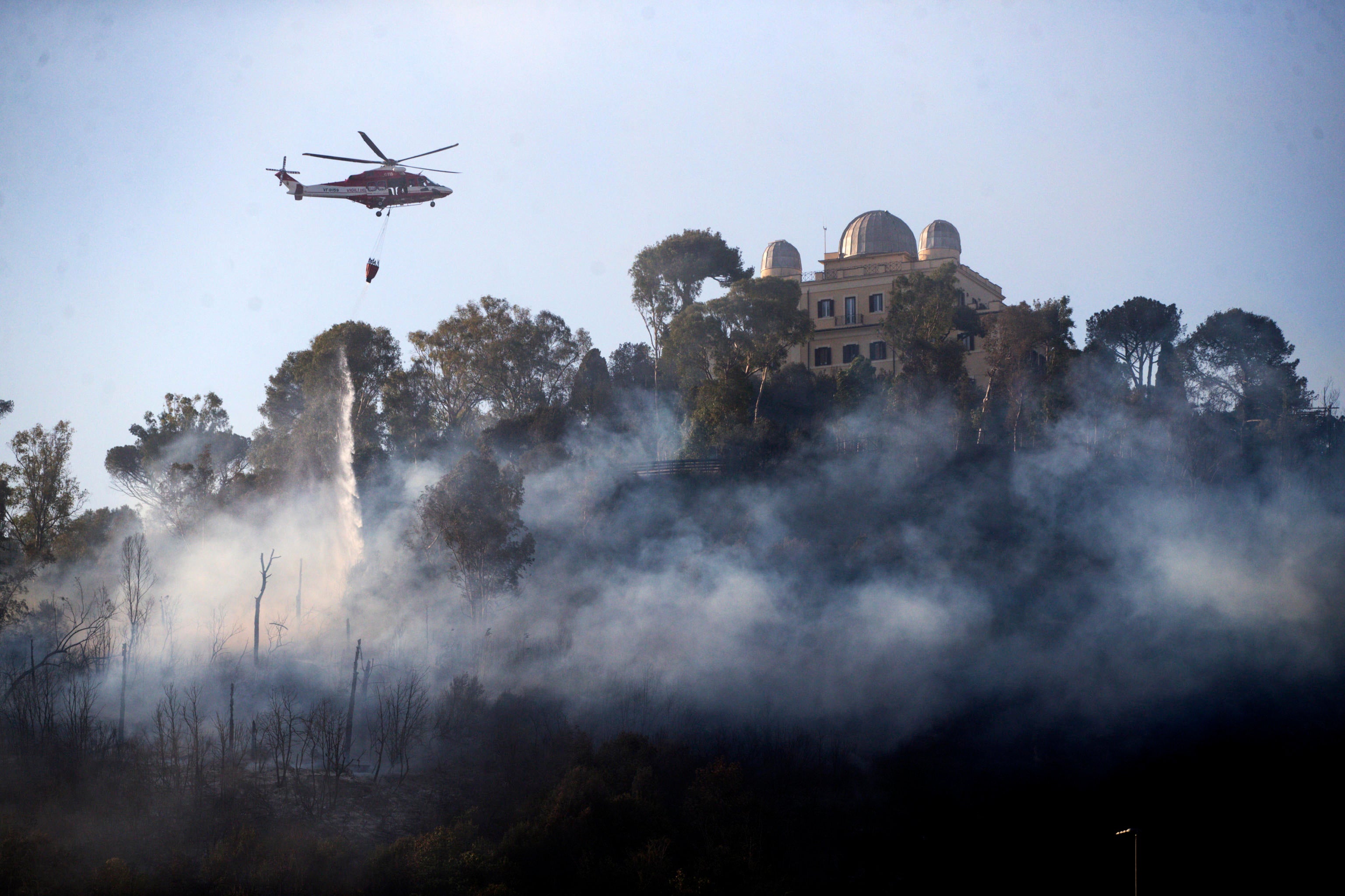 A fire brigade helicopter drops water over a large fire that broke out in the Monte Mario area in Rome