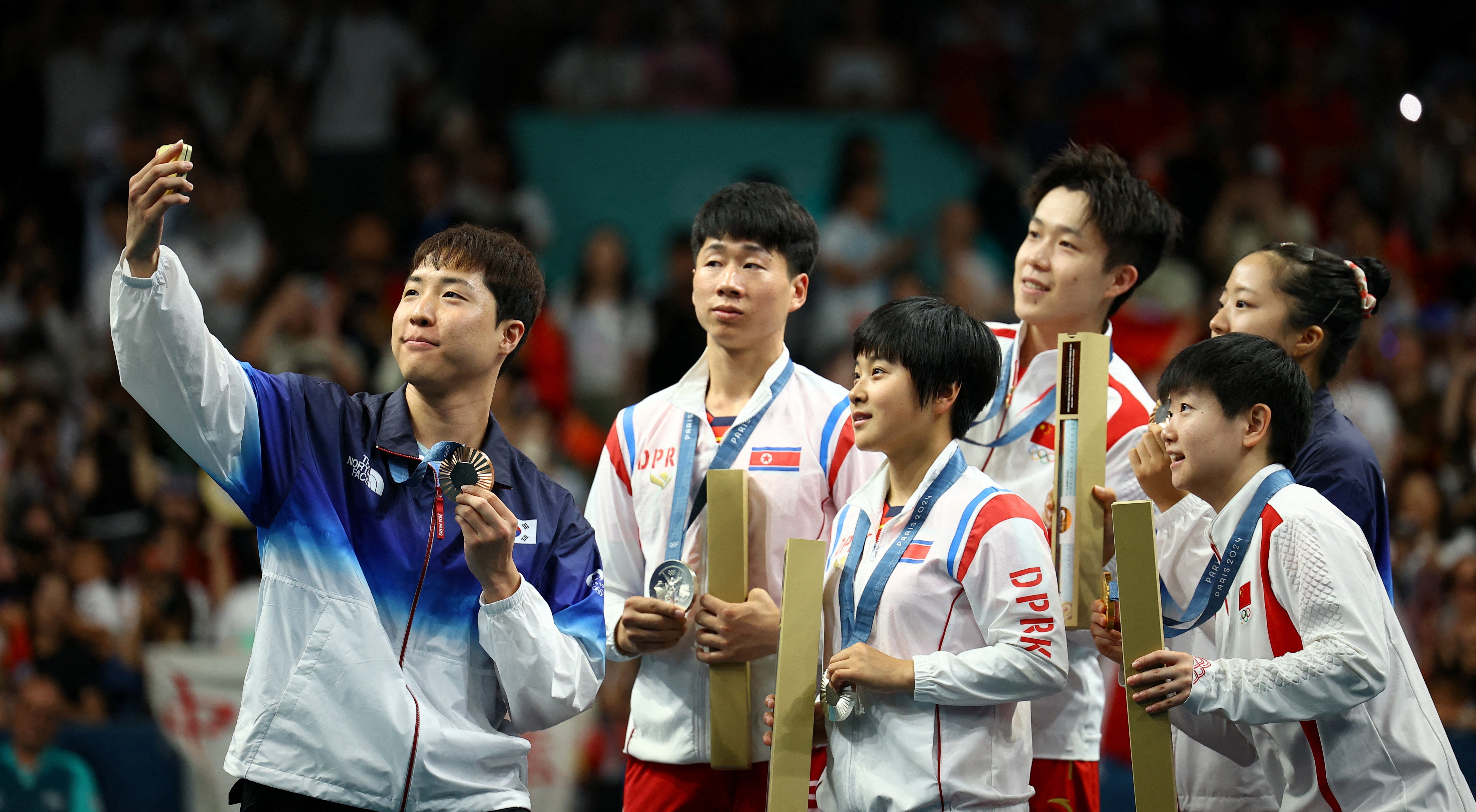 Bronze medallist Jonghoon Lim of South Korea takes selfie with Yubin Shin of South Korea and gold medallists Chuqin Wang of China and Yingsha Sun of China with silver medallists Jong Sik Ri of North Korea and Kum Yong Kim of North Korea