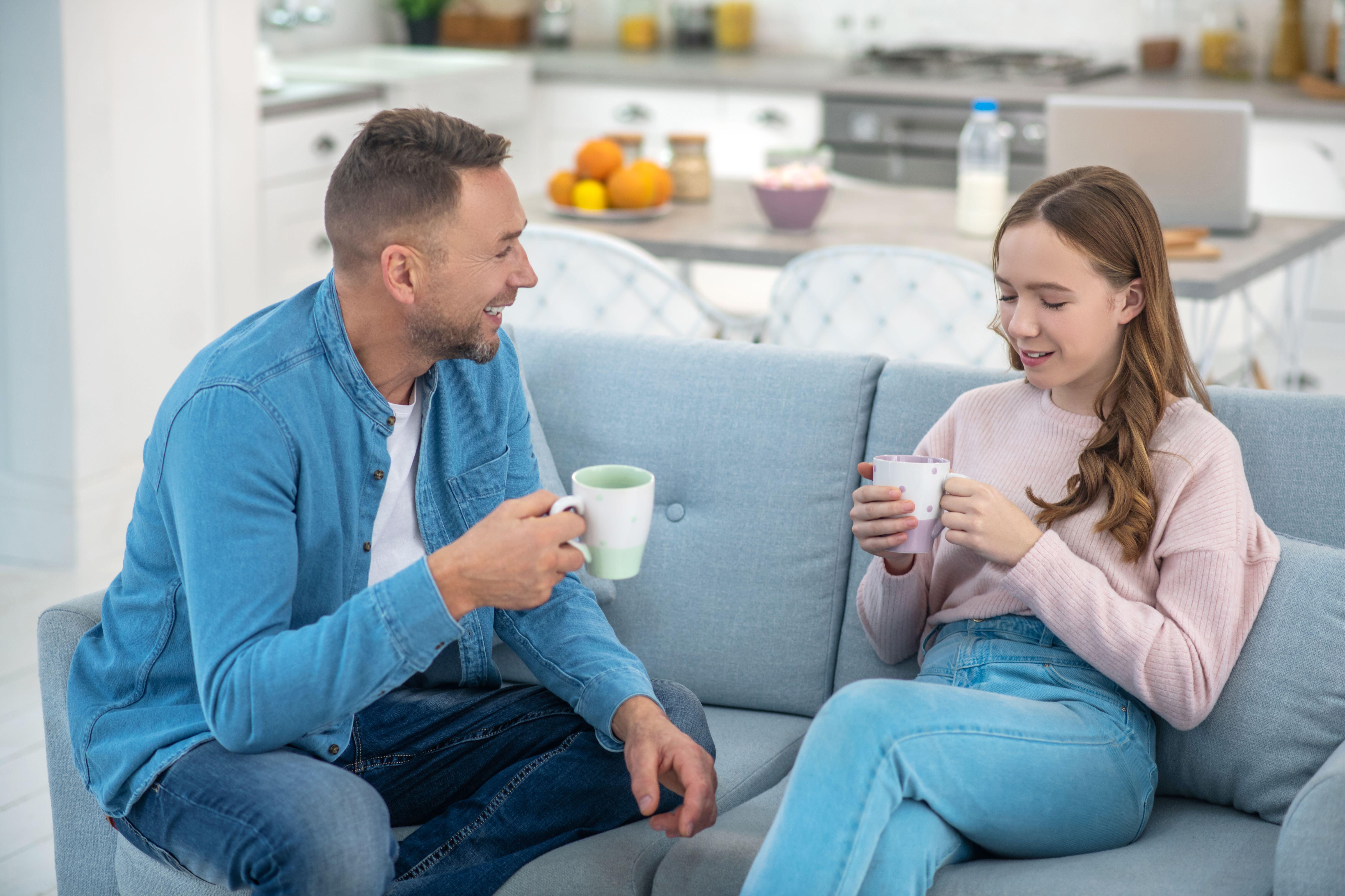 Father and daughter smiling and chatting on the sofa (Alamy/PA)