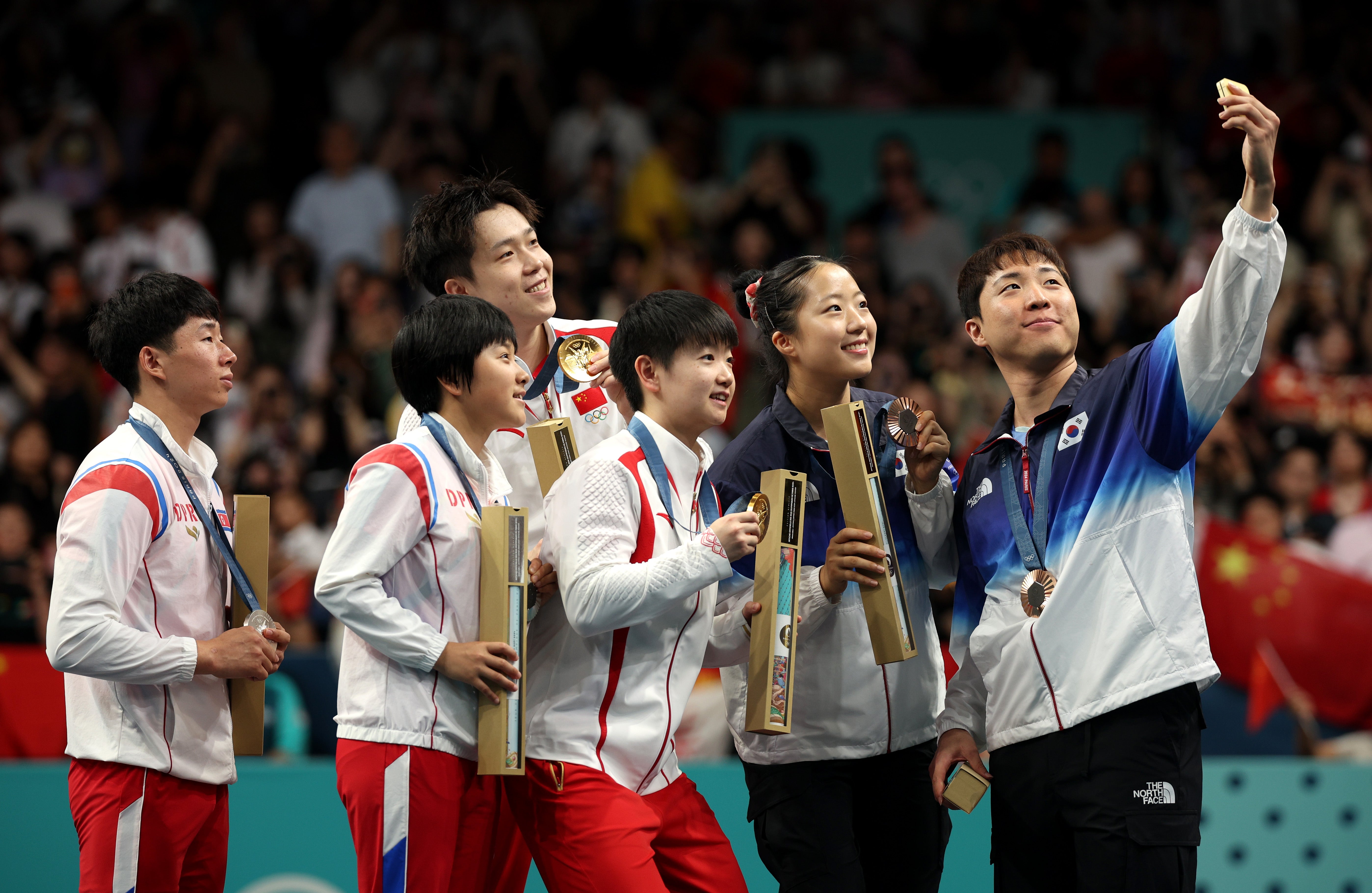 Gold medalists, Chuqin Wang and Yingsha Sun of Team Peopleâs Republic of China (C), silver medalists Jong Sik Ri and Kum Yong Kim of Team Democratic Peopleâs Republic of Korea (L) and Bronze Medalists, Jonghoon Lim and Yubin Shin of Team Republic of Korea (R) pose for a selfie on the podium after the Table Tennis Mixed Doubles