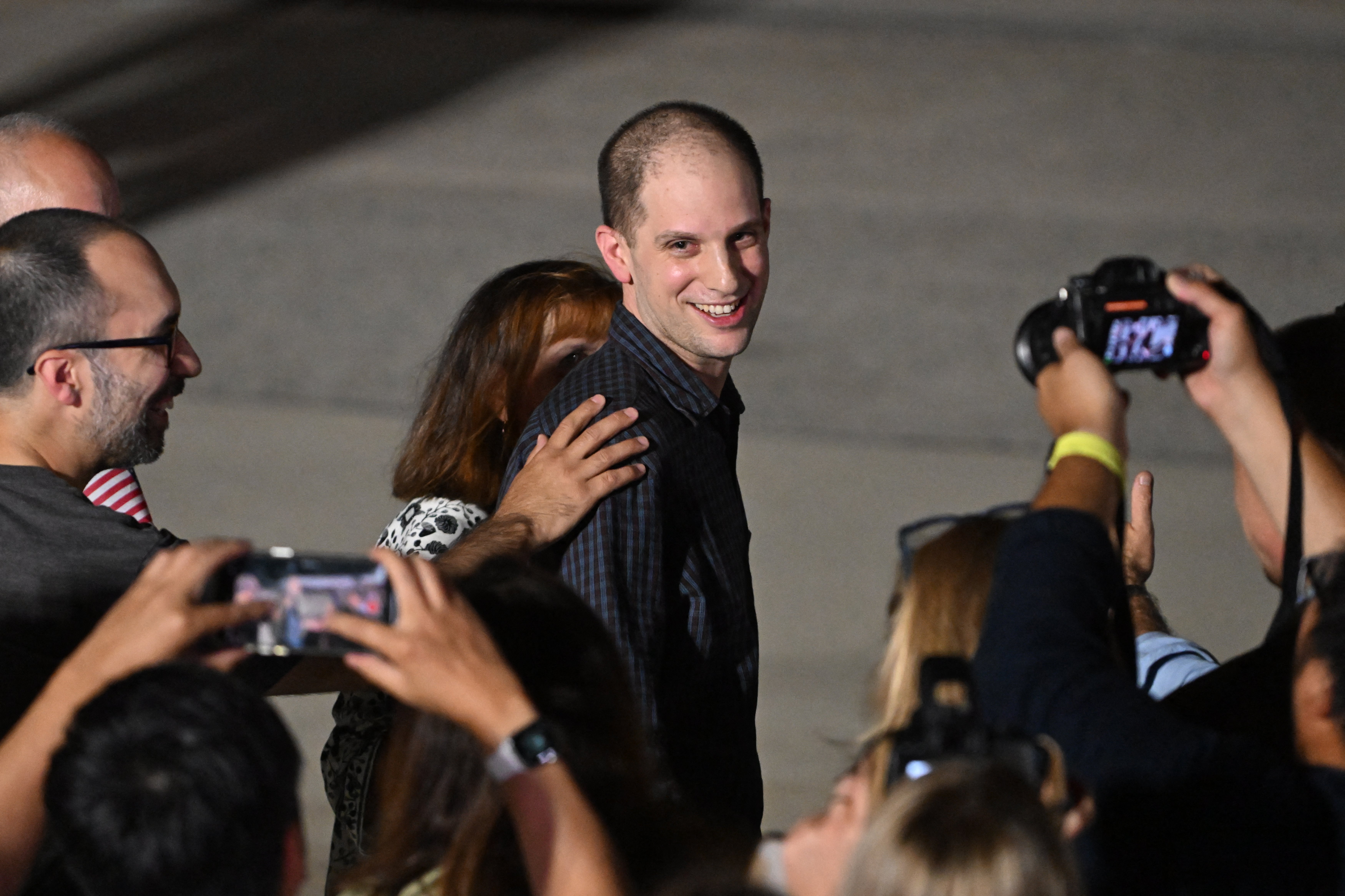 Former prisoner held by Russia US journalist Evan Gershkovich smiles as he walks with his mother Ella Milman at Joint Base Andrews in Maryland on 1 August 2024