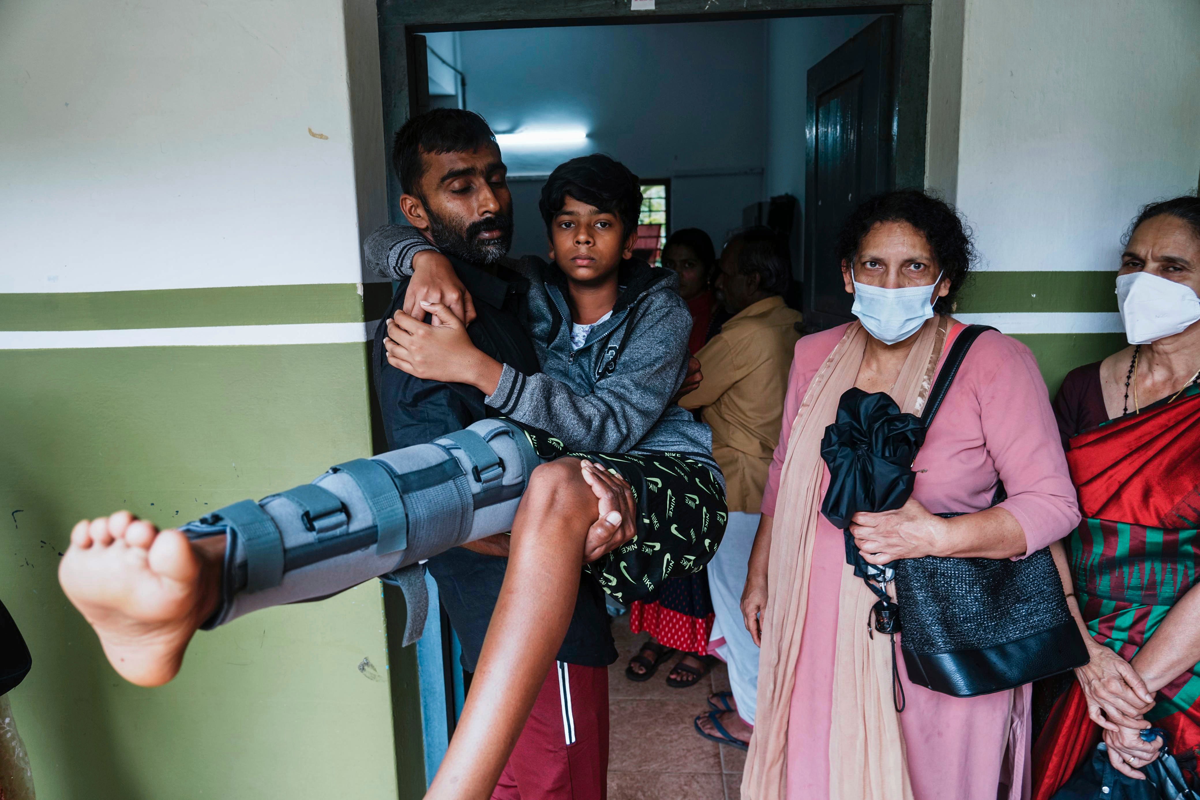 Prajesh Tindu carries his brother Alban Tindu at a government-run relief camp for survivors set up at a school building third day after landslides set off by torrential rains in Wayanad