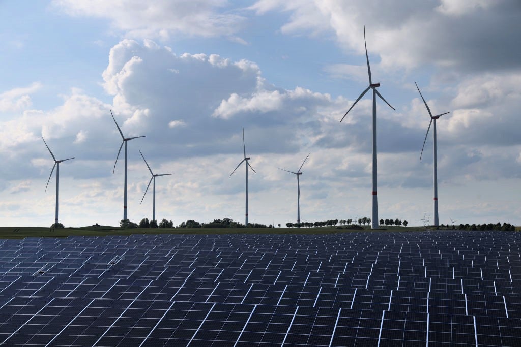 Wind turbines spin behind a solar energy park on 2 June, 2022 near Prenzlau, Germany