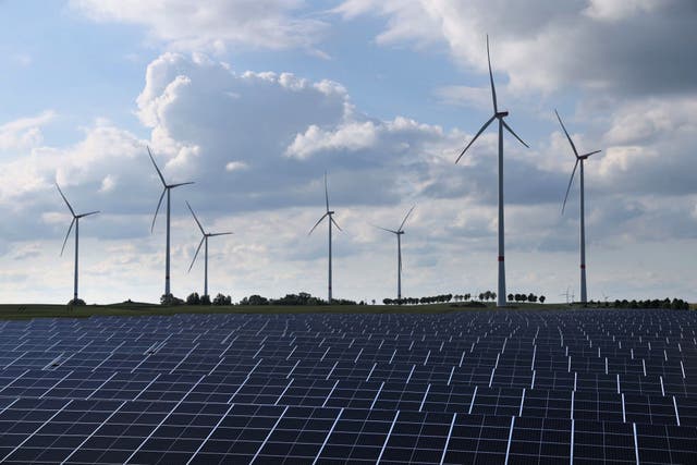 <p>Wind turbines spin behind a solar energy park on 2 June, 2022 near Prenzlau, Germany</p>