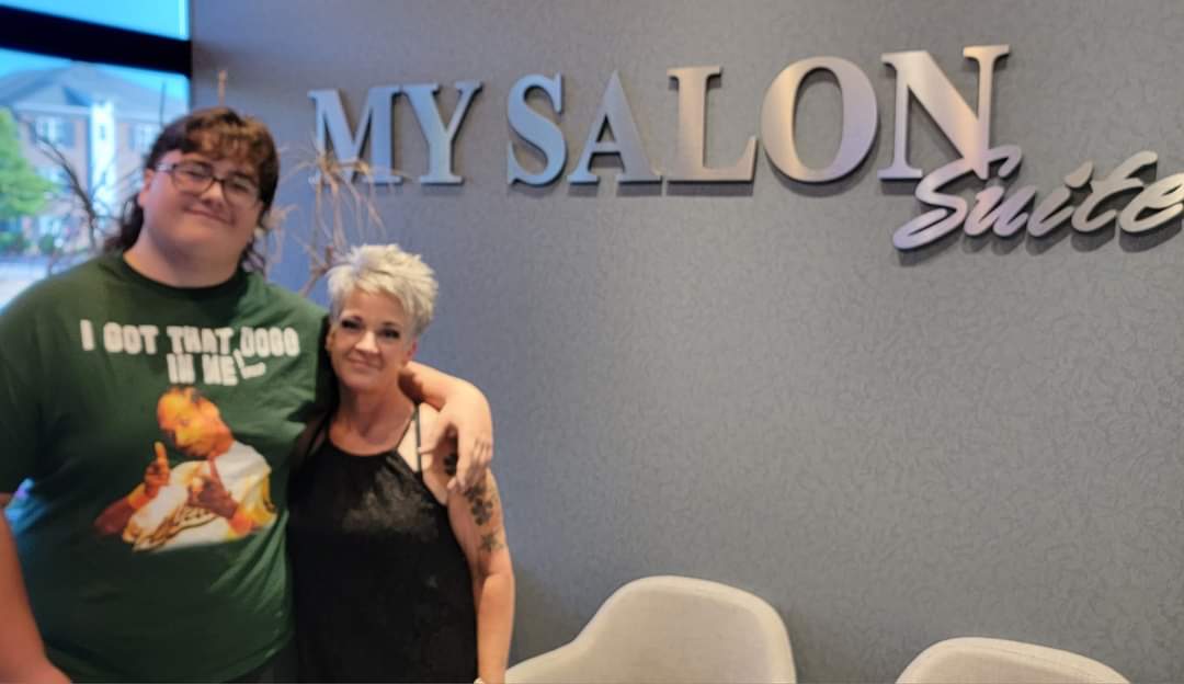 Will Joyner poses with the hairdresser who cuts and helps maintain his mullet – though he proudly points out the curls are natural