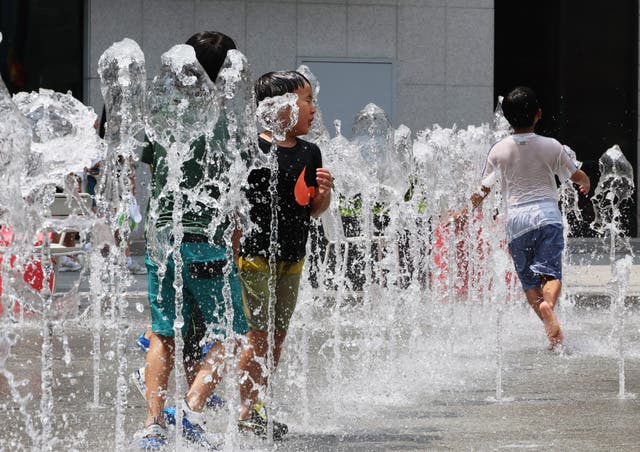 <p>Children play and cool off between the water jets of a fountain in Gwanghwamun Square in downtown Seoul, South Korea</p>