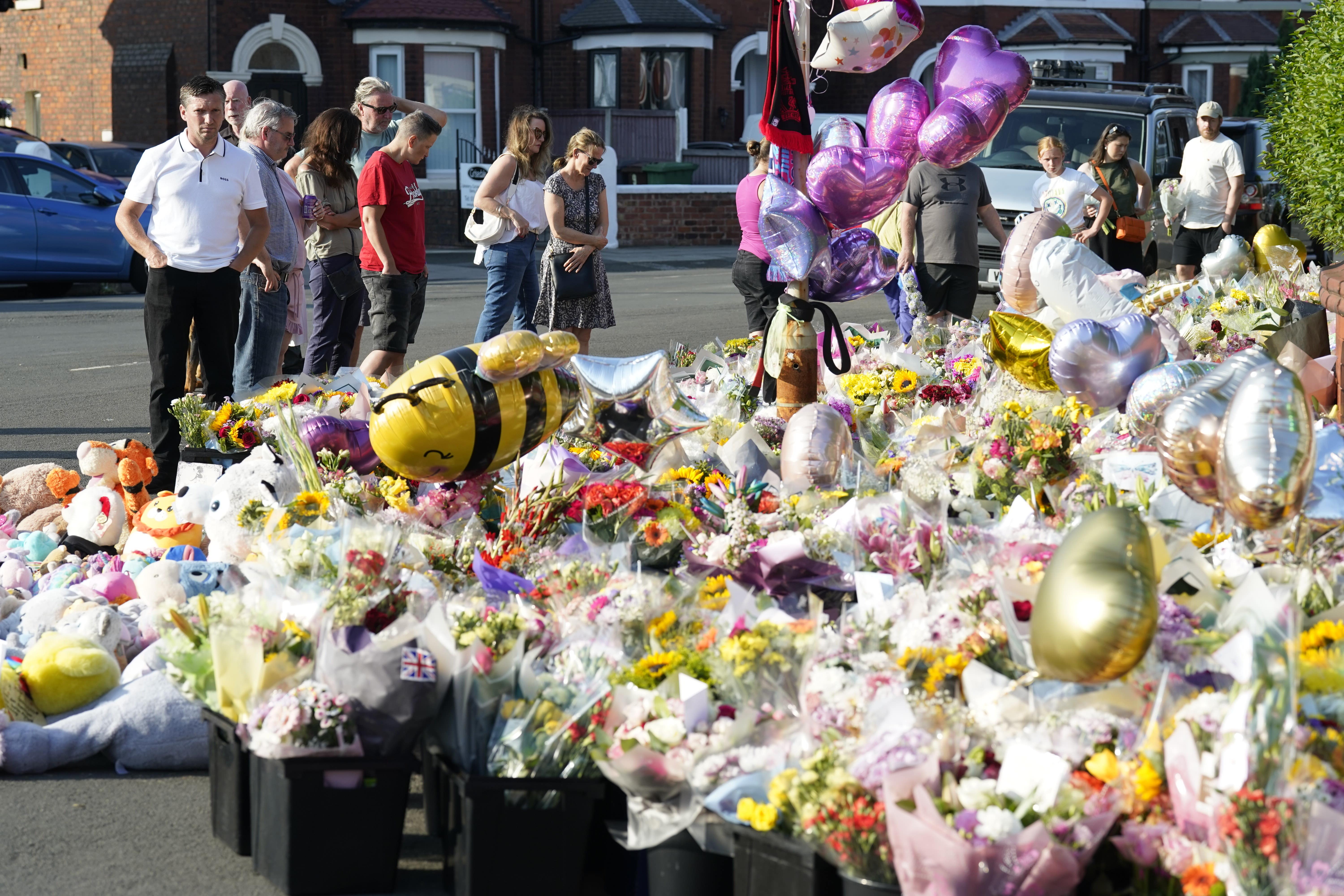 People look at floral tributes on Maple Street, Southport (Danny Lawson/PA)