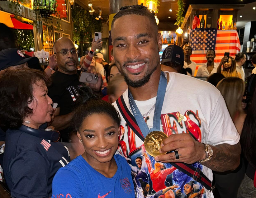 Jonathan Owens poses with Simone Biles while wearing his gold medal