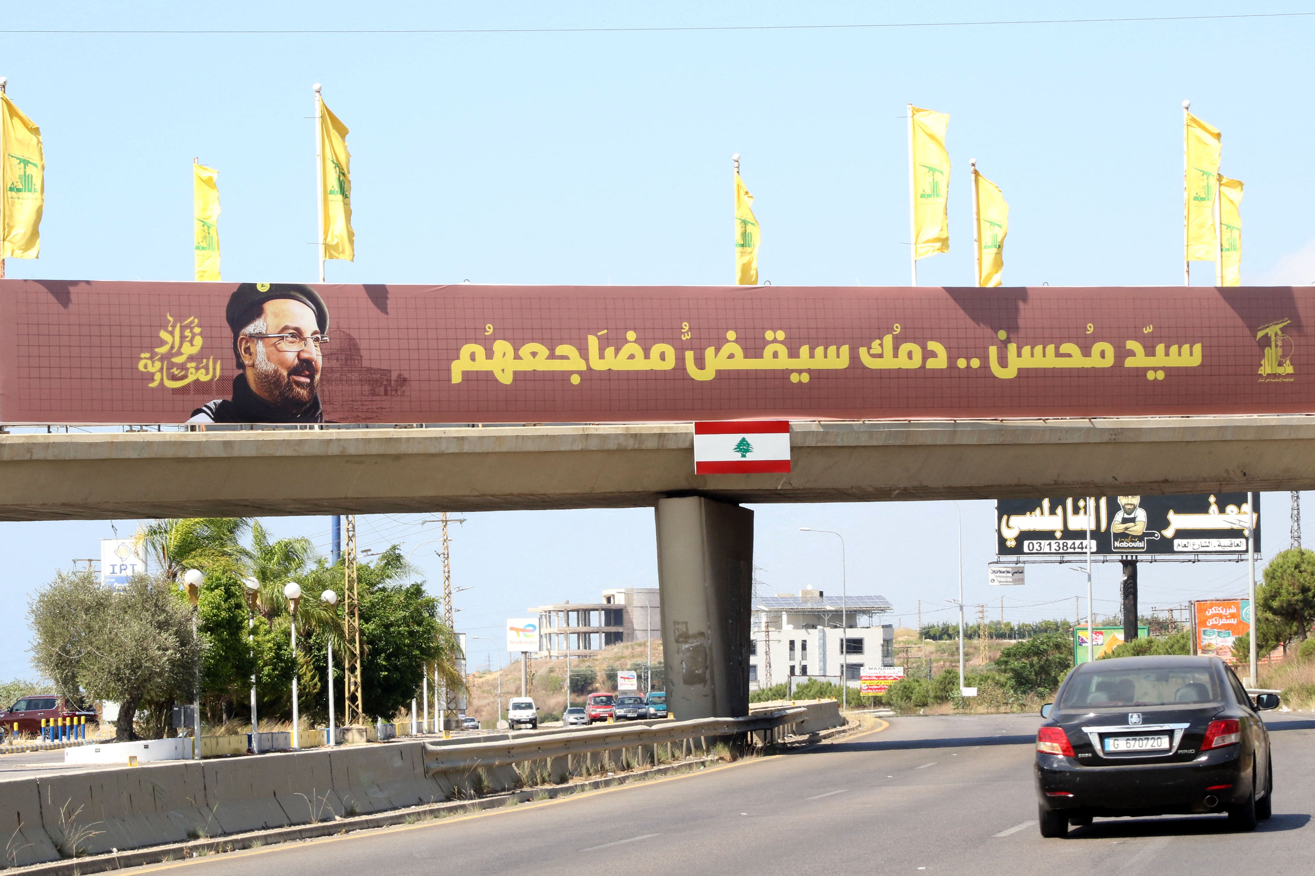 Yellow Hezbollah party flags are erected along with a banner showing assassinated Hezbollah top commander Fuad Shukr, placed along a walk way across the Sidon-to-Tyre highway, in southern Lebanon