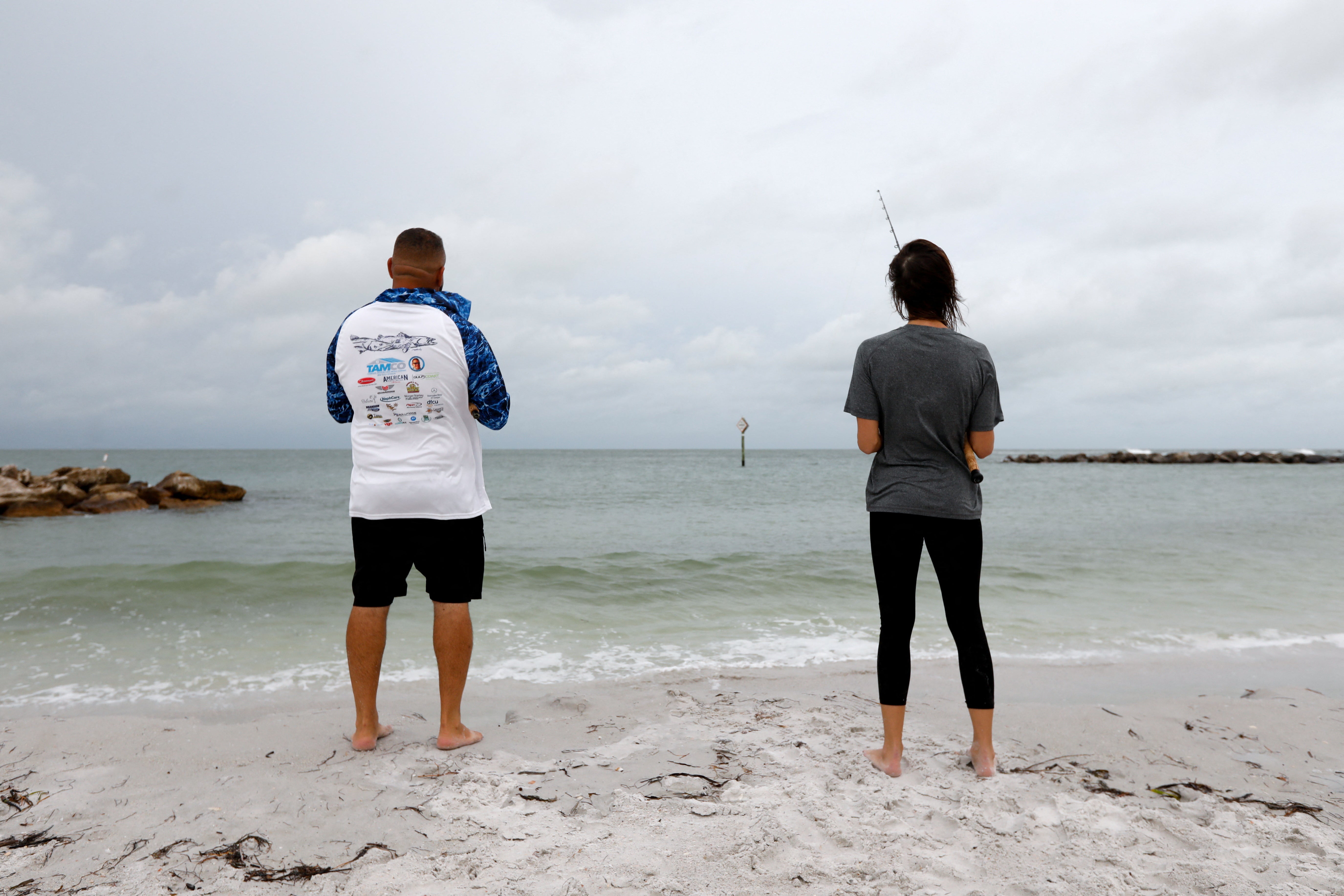 Beachgoers fish during cloudy weather on Sunday at St. Pete Beach, Florida as Tropical Storm Debby approaches the Gulf Coast