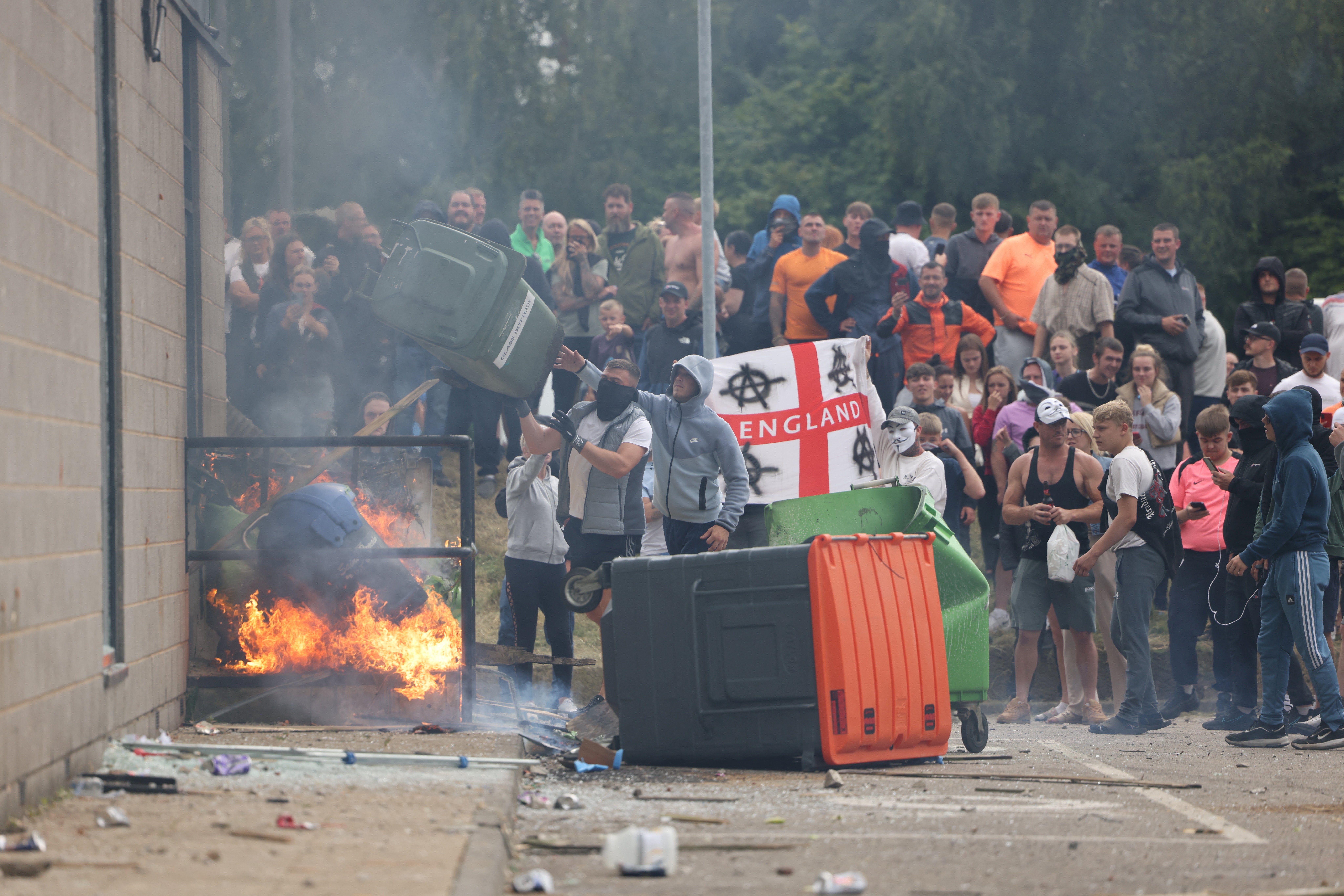 A large mob gathers outside the Holiday Inn Express in Manvers, a suburb in Rotherham, before hurling debris at police on Sunday