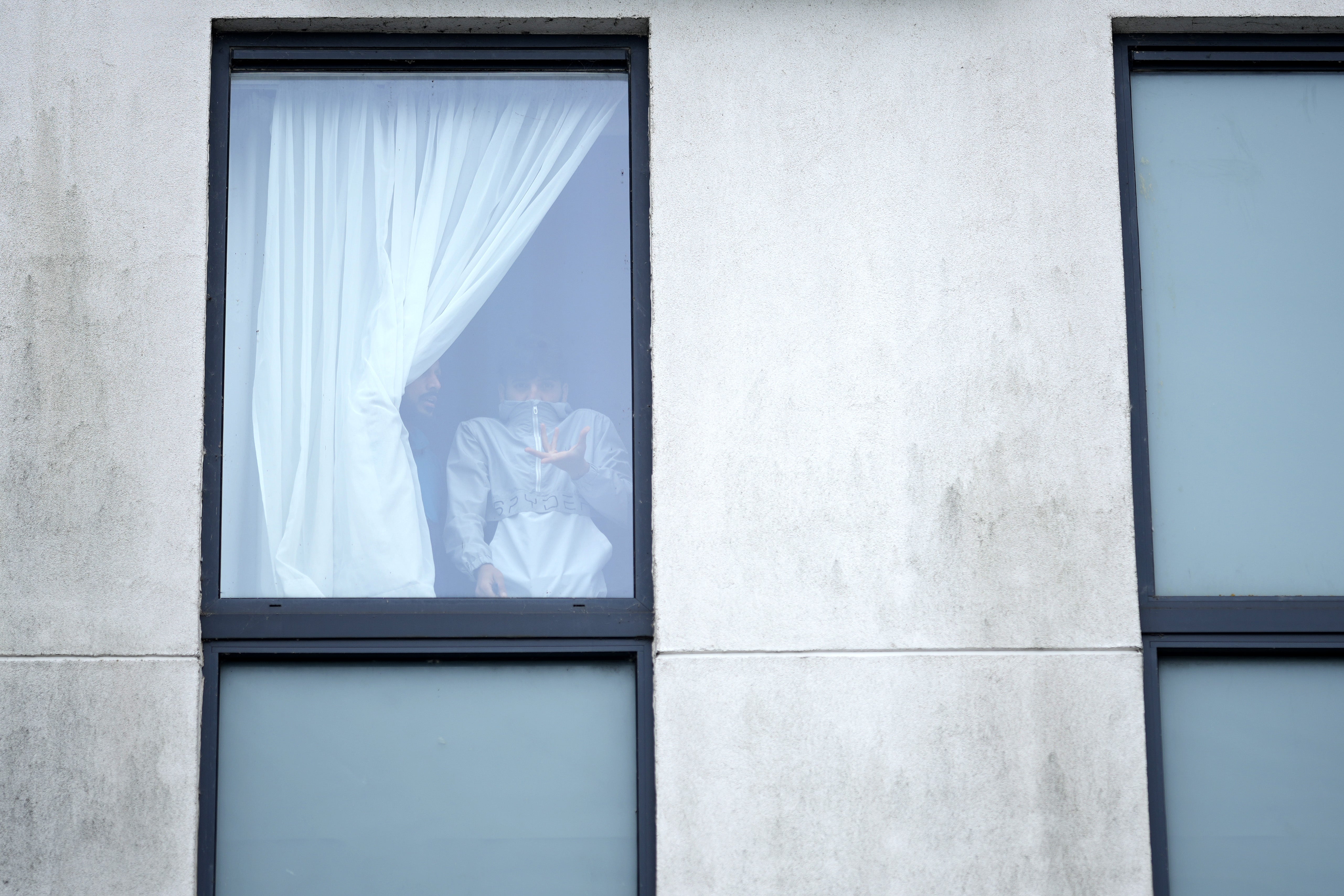 A migrant watches on from the Holiday Inn’s window as a mob attacks the building