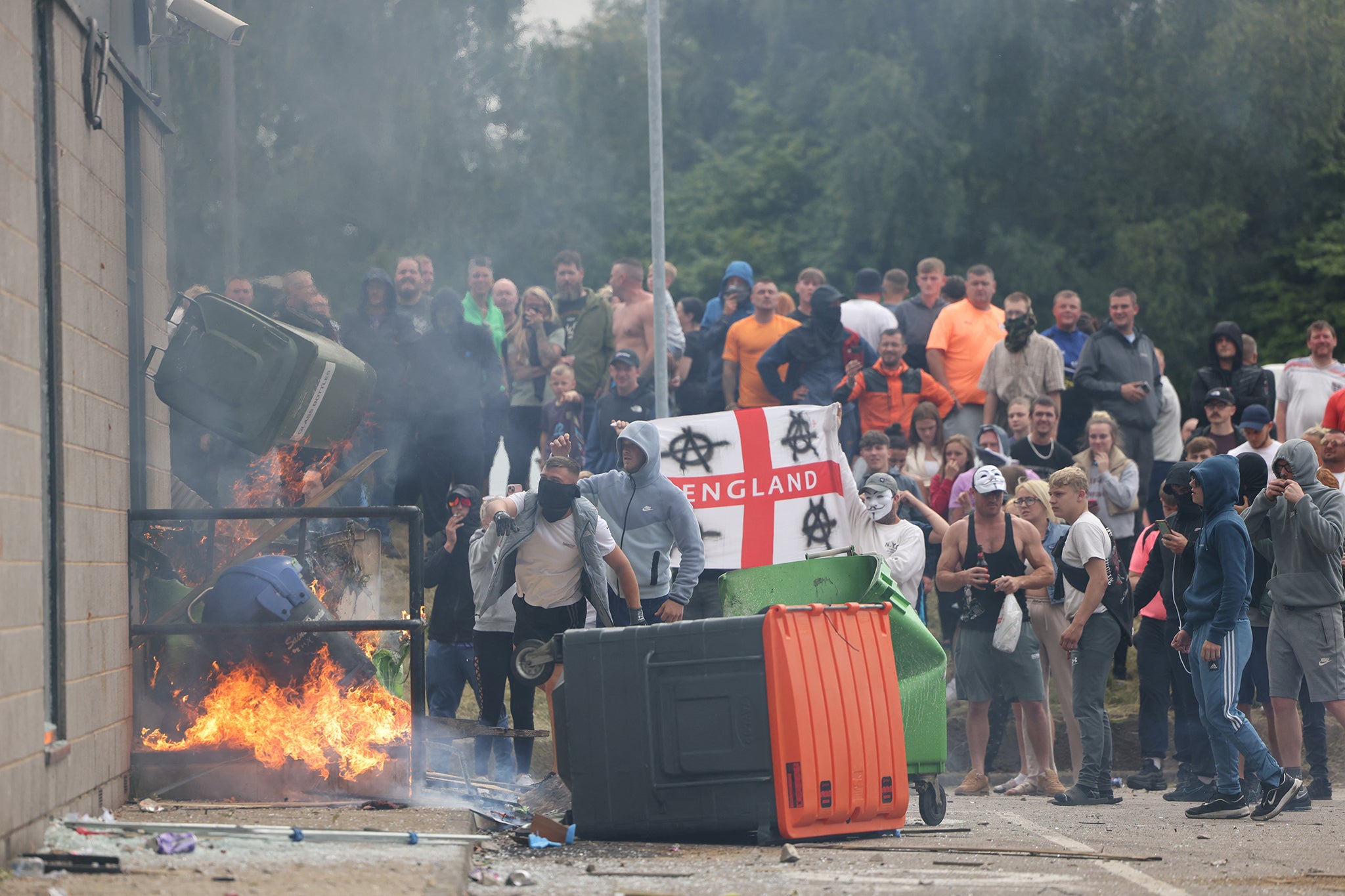 Rioters throw a garbage bin on fire towards a hotel in Rotherham on Sunday