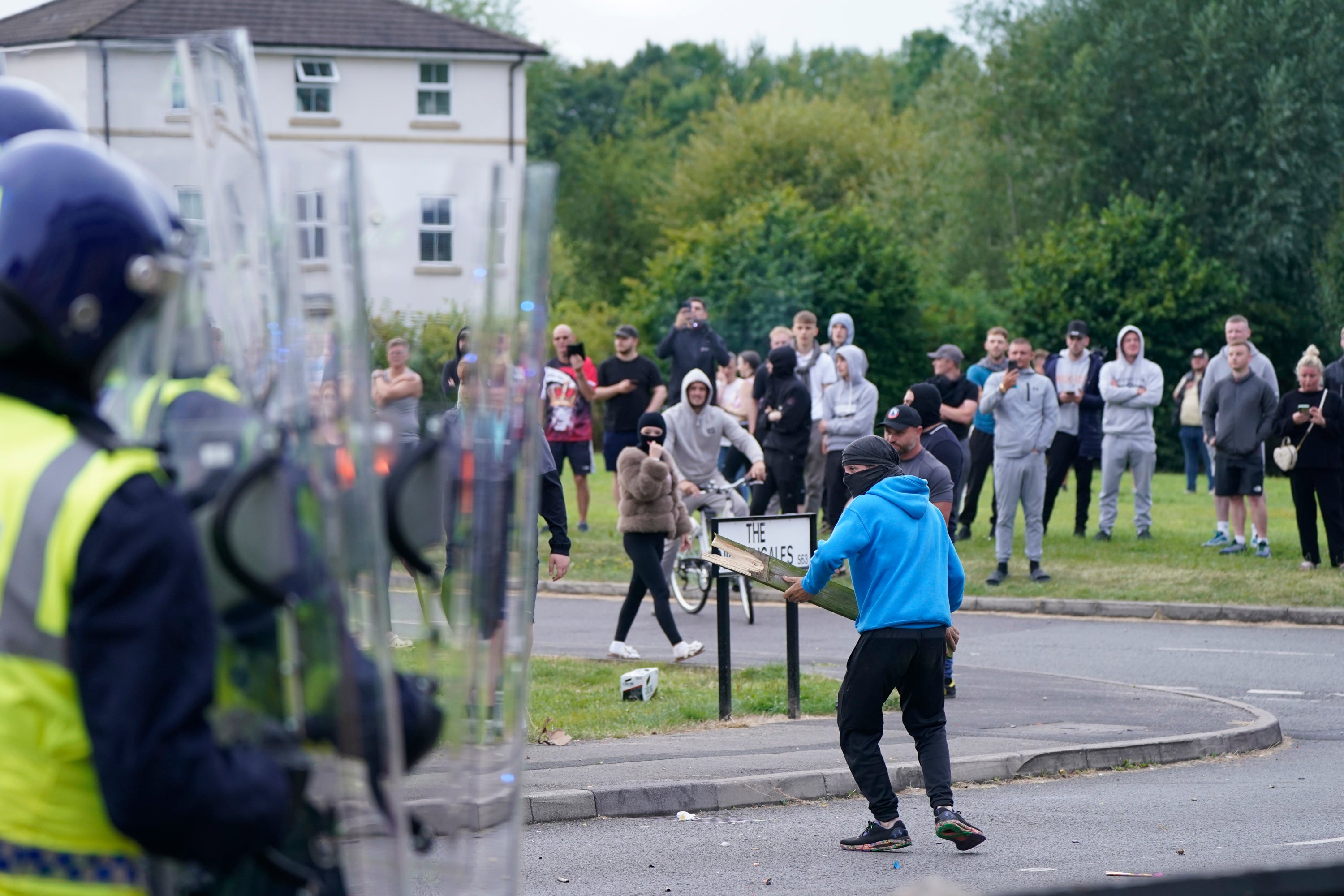 A youth aims a fence post towards police near the Holiday Inn Express in Rotherham,