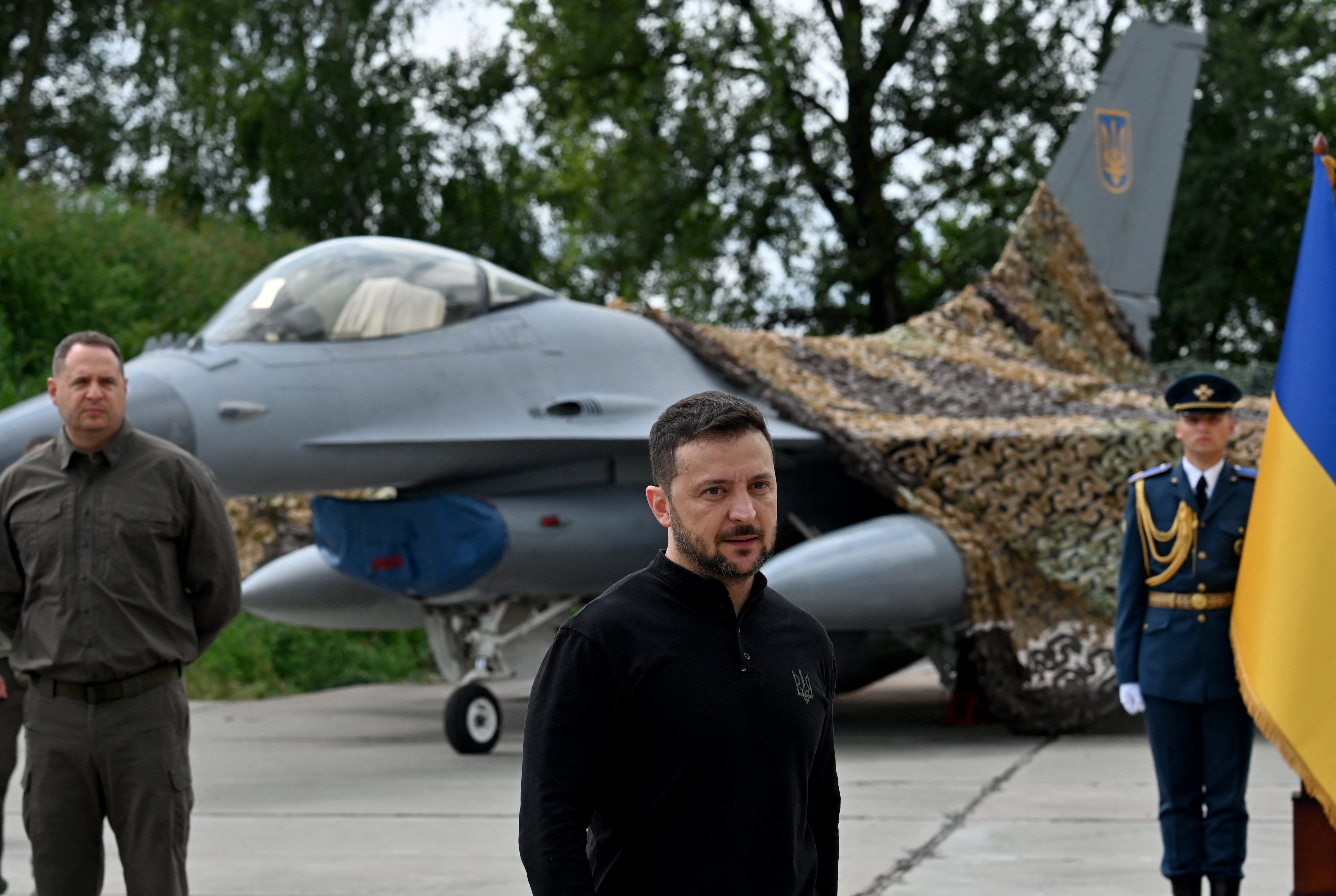 Volodymyr Zelensky (C) stands in front of an F-16 fighter jet during a ceremony held to mark Ukrainian Air Forces Day