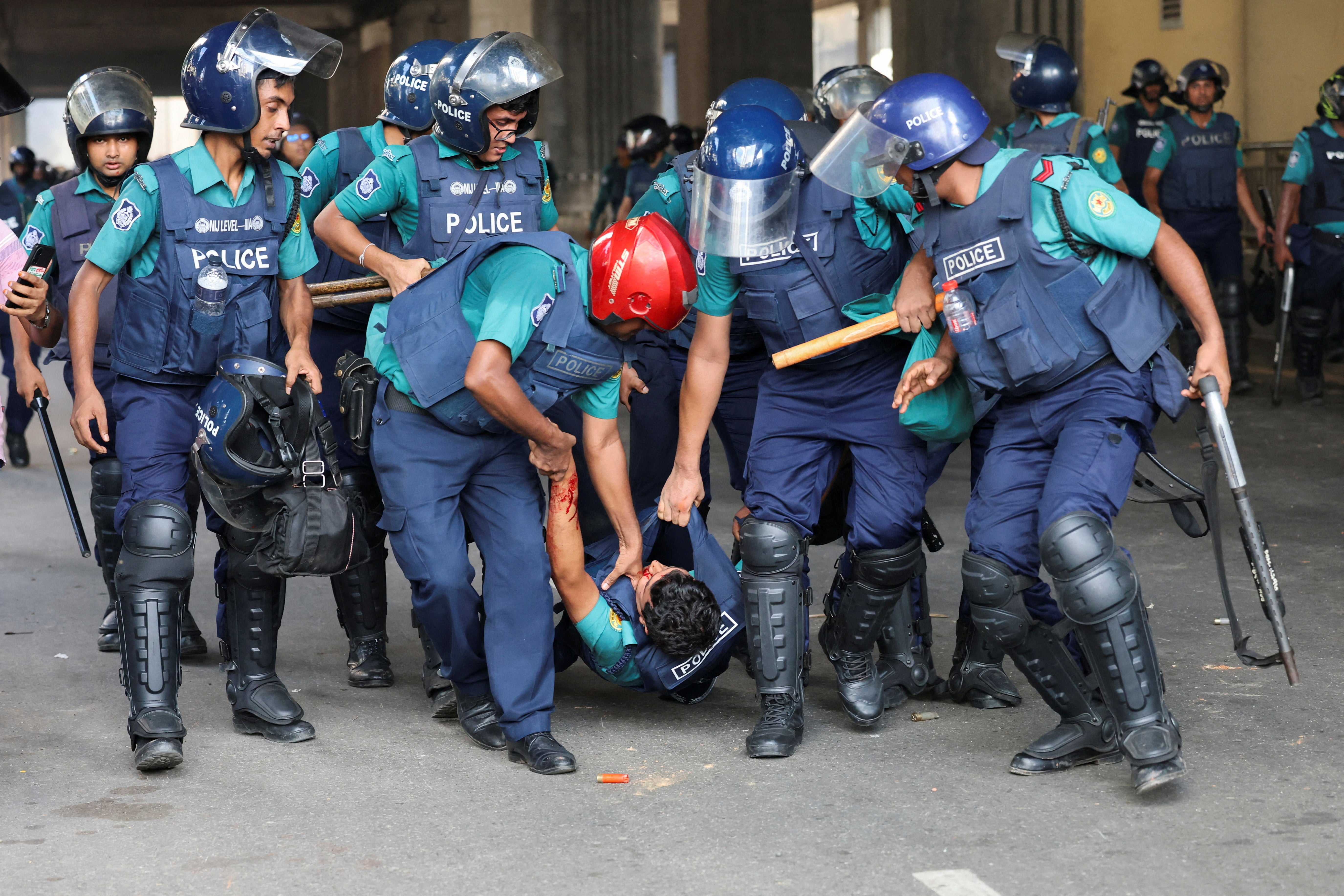 <p>Police carry a wounded officer during a clash with protesters in Dhaka</p>