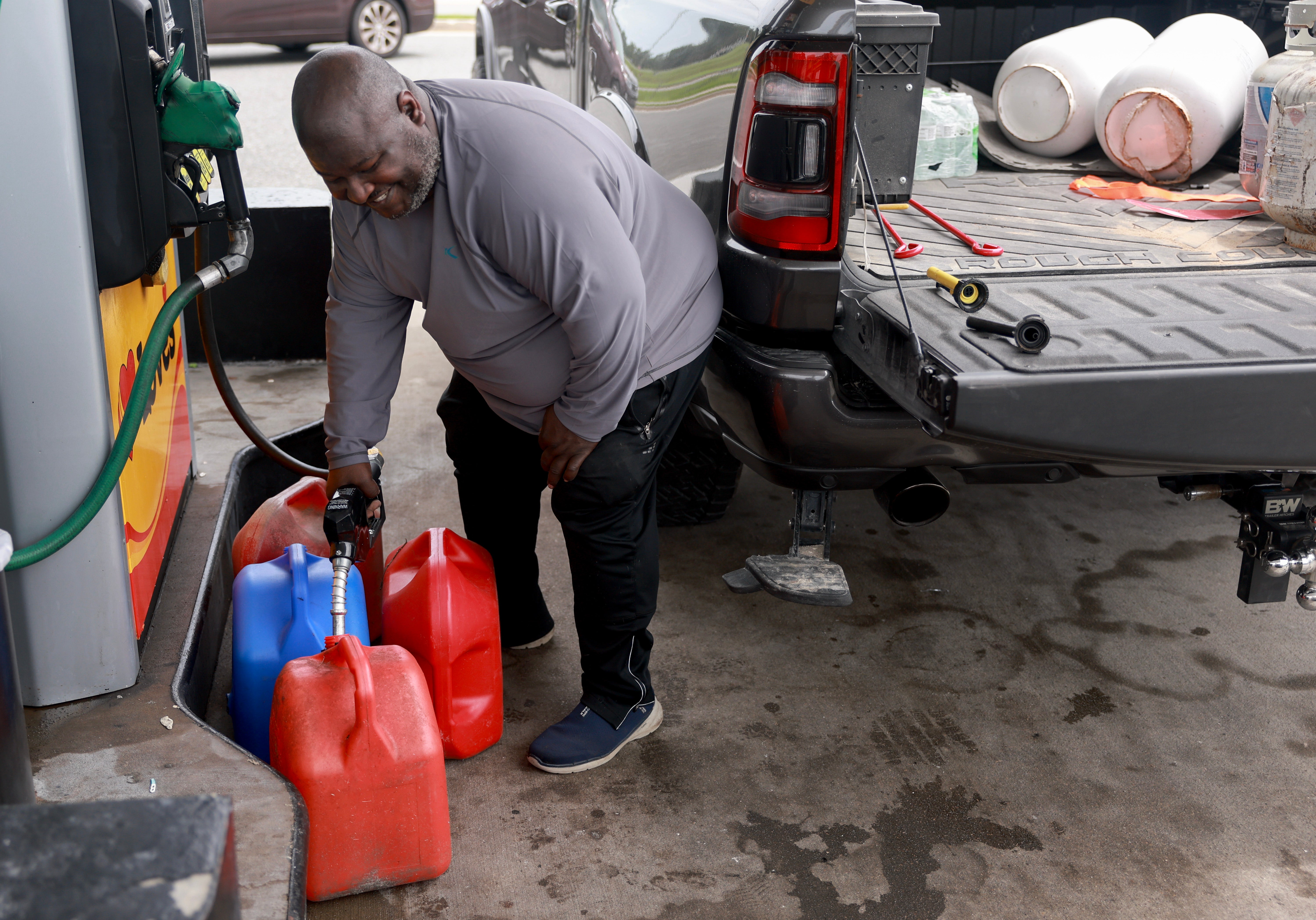 A resident, Jessie Walker, fills containers with fuel as he prepares for the arrival of Hurricane Debby in Lee, Florida