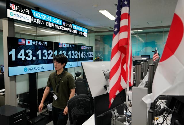 <p>A dealer walks next to monitors showing foreign exchange rates in Tokyo, Japan, on 5 August 2024</p>