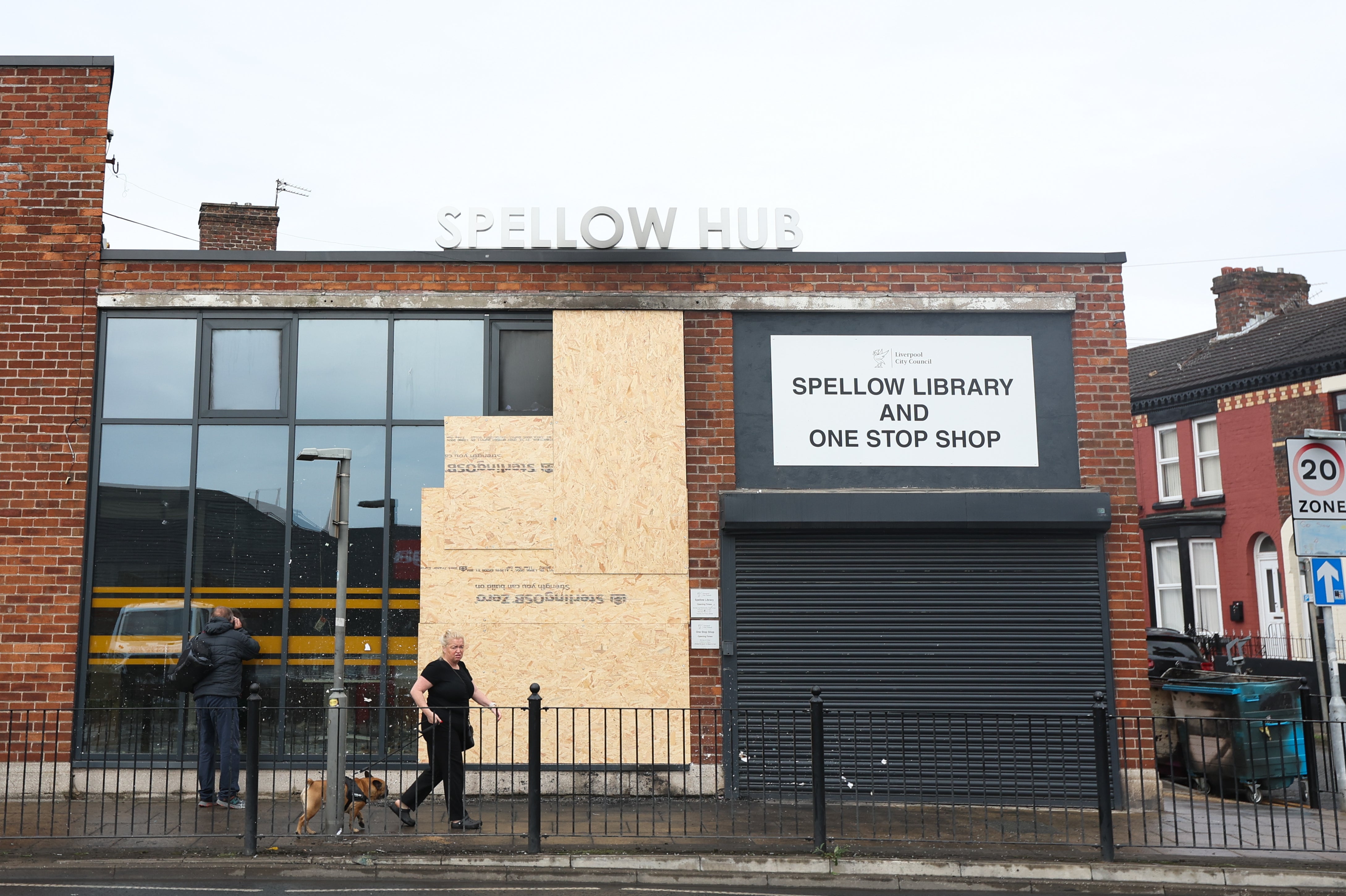 People look at damage to the Spellow Hub community library after a night of violent disorder in Liverpool