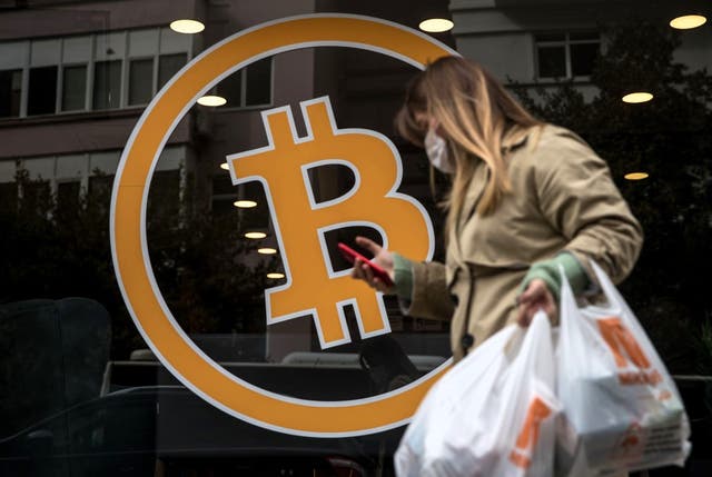 <p>A woman walks past a bitcoin logo at the entrance of a cryptocurrency exchange office on 16 April, 2021 in Istanbul, Turkey</p>