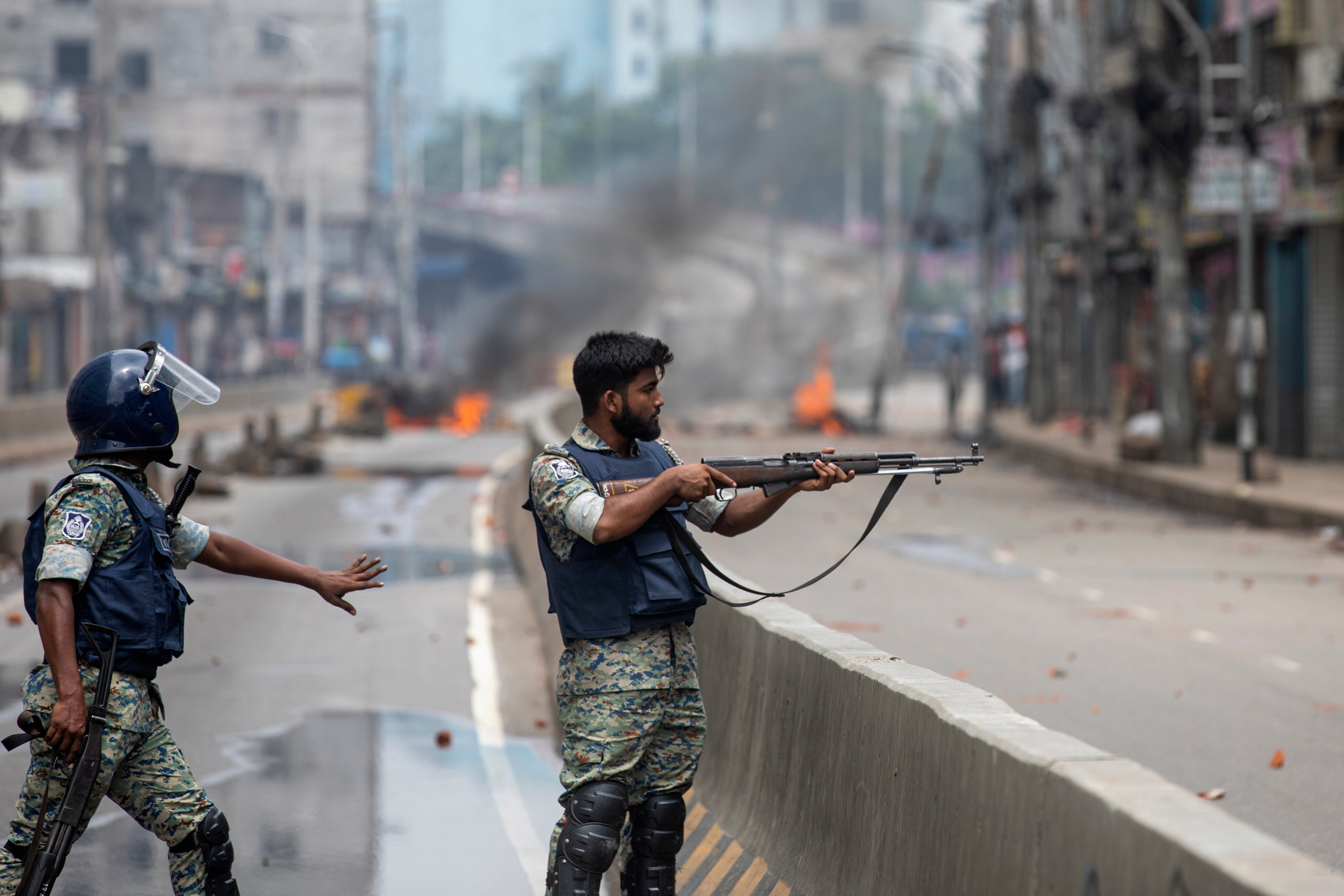 A policeman aims his weapon at protesters during a curfew imposed following violence during protests against Sheikh Hasina and her government, in Dhaka, Bangladesh, Monday, 5 Aug 2024