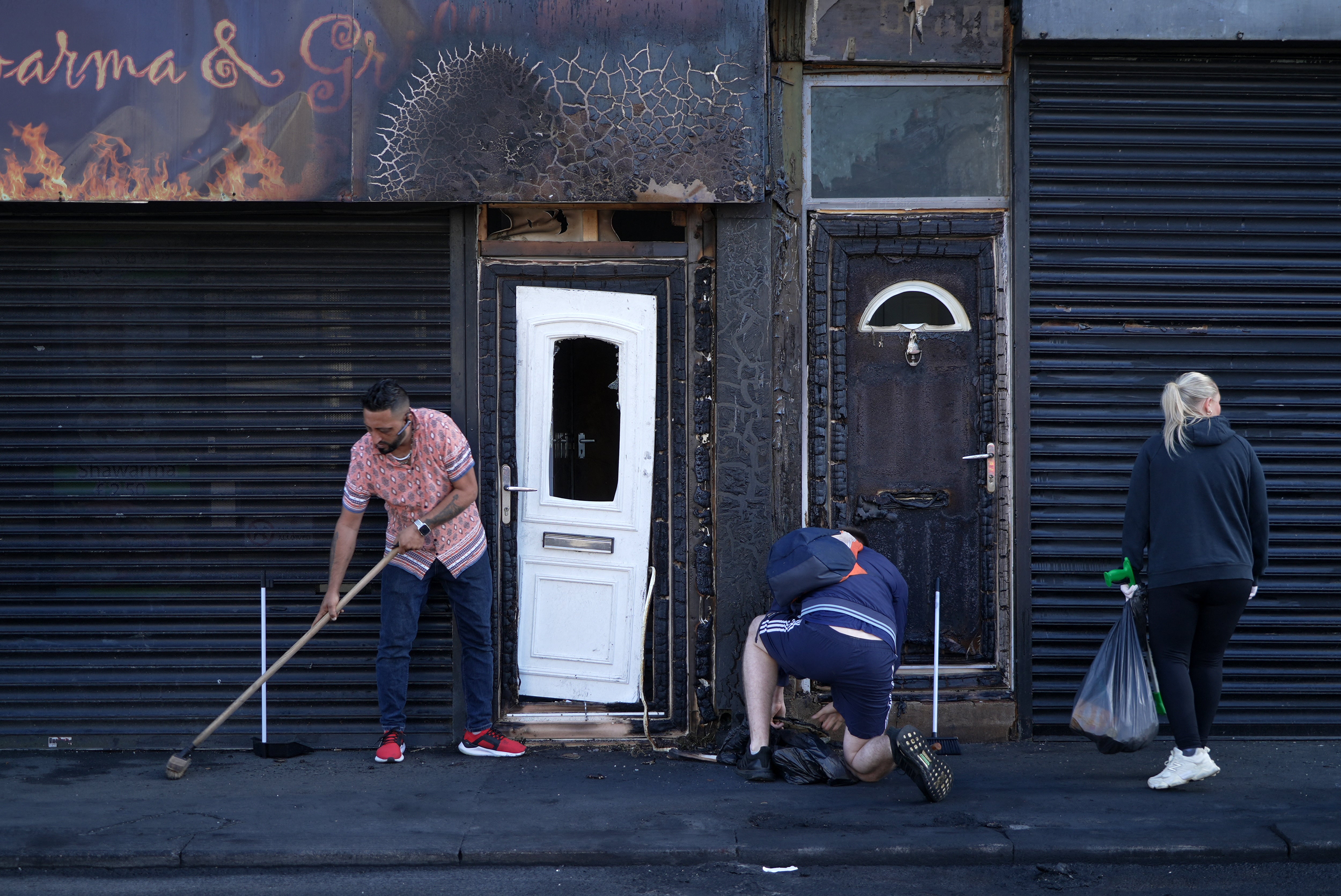 Restaurant owner Luqman Khan clears debris from the street in front of his restaurant in Middlesbrough