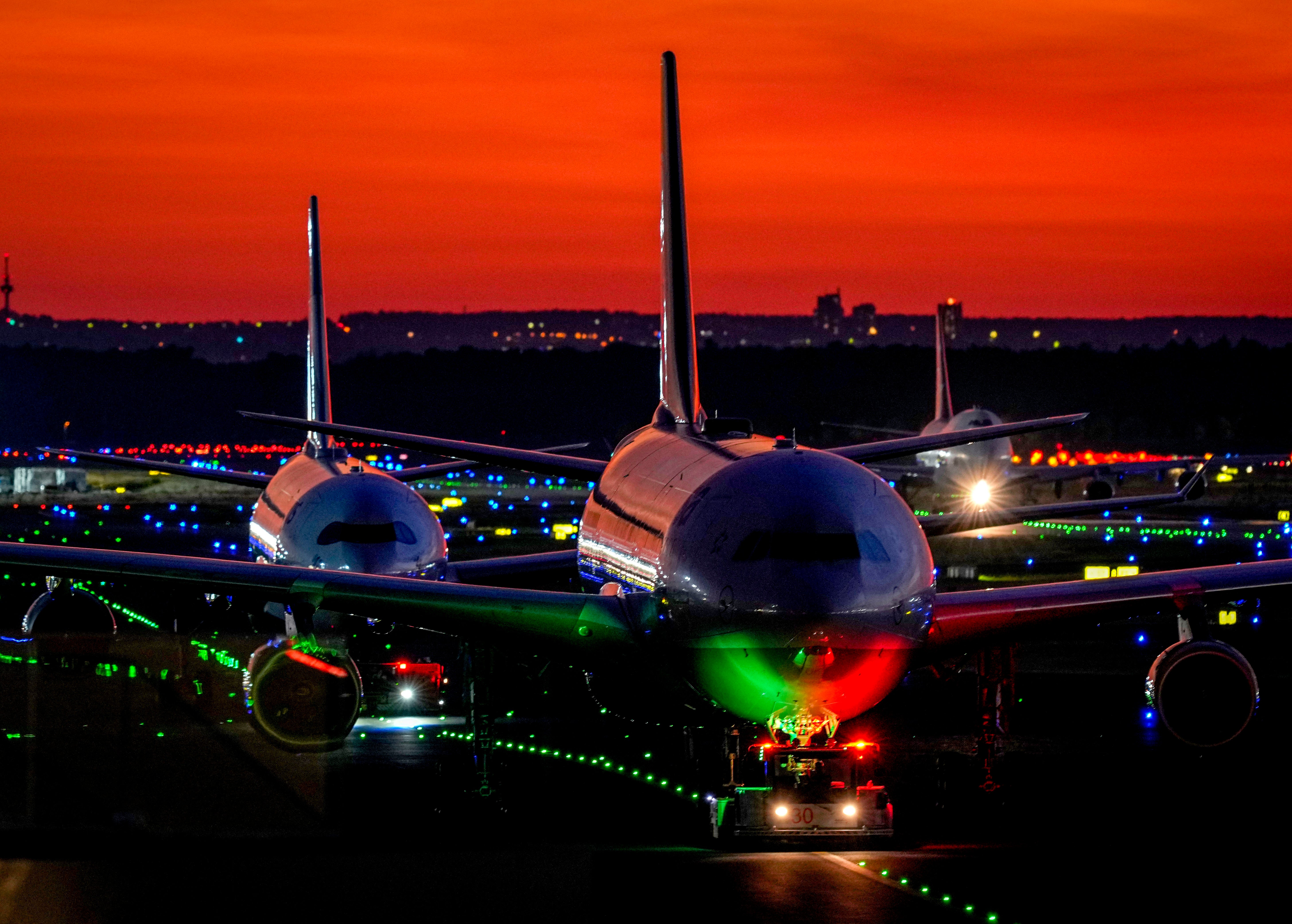 Aircrafts roll over a runway at the airport in Frankfurt, Germany, after sunset on Thursday, Sept. 23, 2021