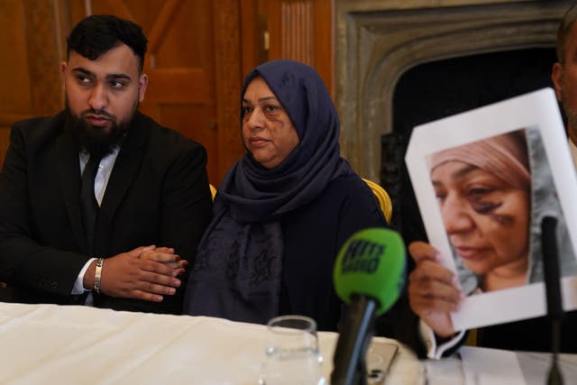 Muhammad Amaad with his mother Shameem Akhtar as solicitor Aamer Anwar holds up a picture of Mrs Akhtar, showing an injury (Owen Humphreys/PA)