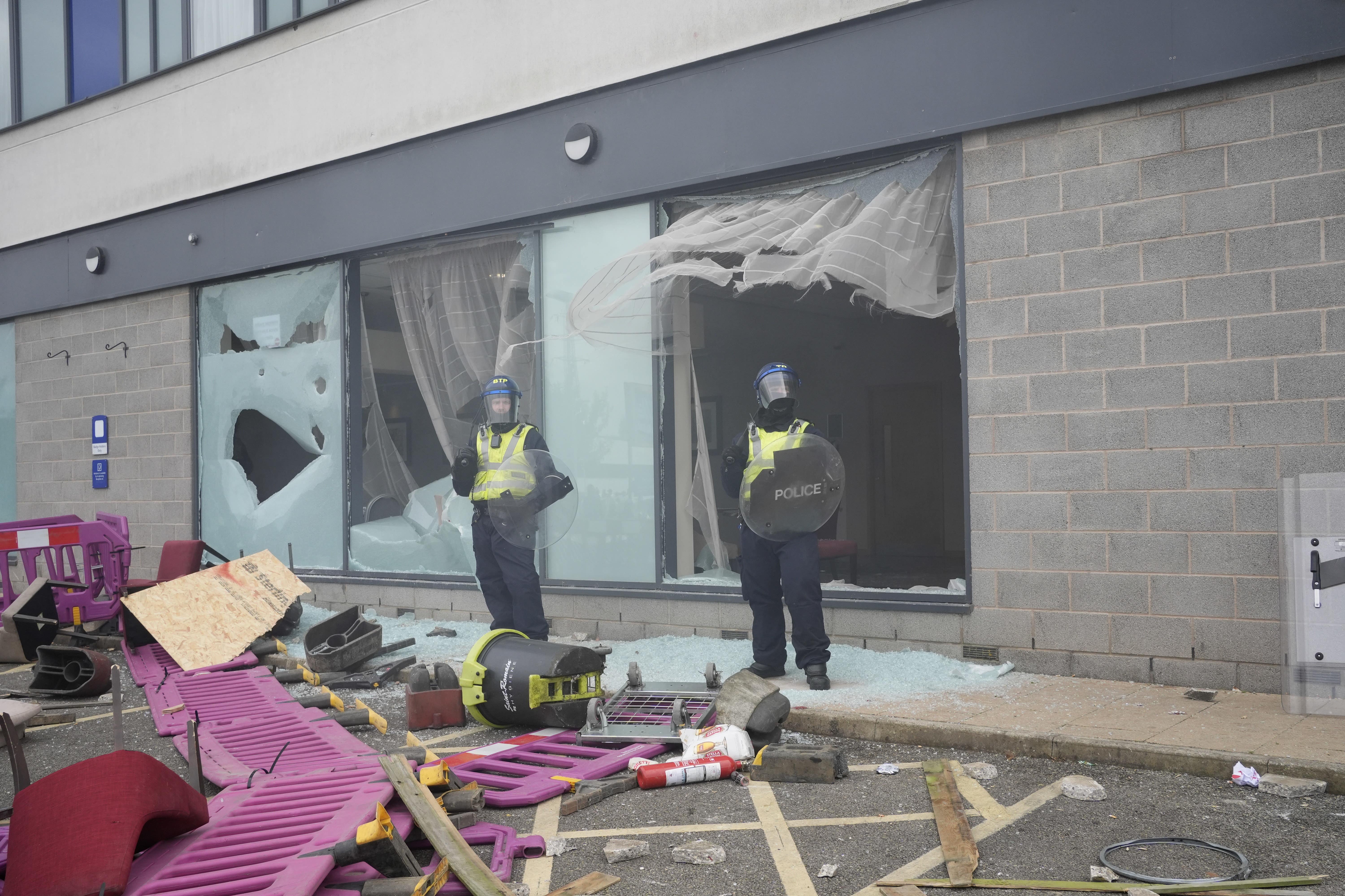 Police officers by smashed windows after trouble flared during an anti-immigration demonstration outside the Holiday Inn Express in Rotherham (Danny Lawson/PA)